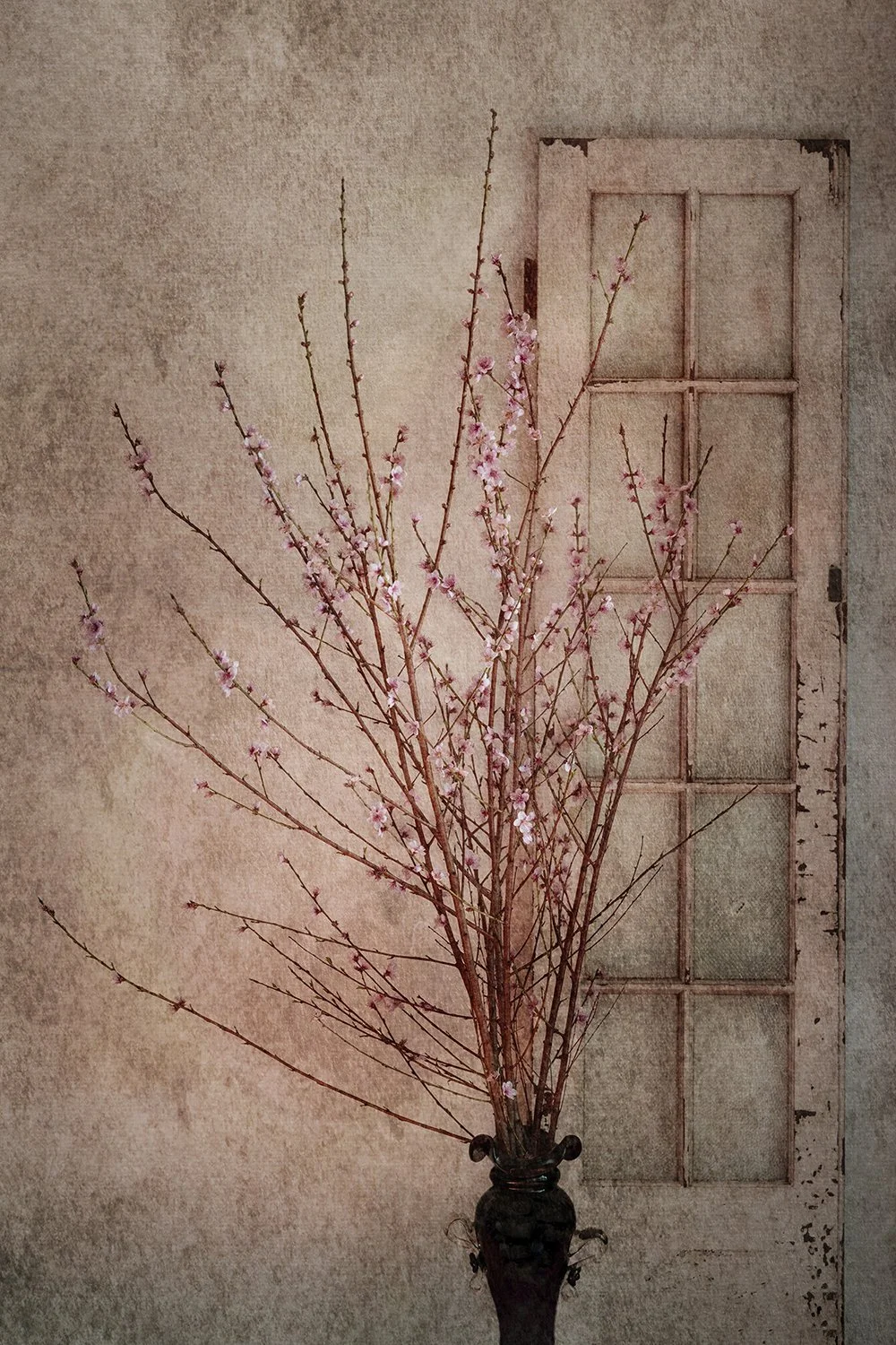 Pink blossom arrangement beside a vintage window.