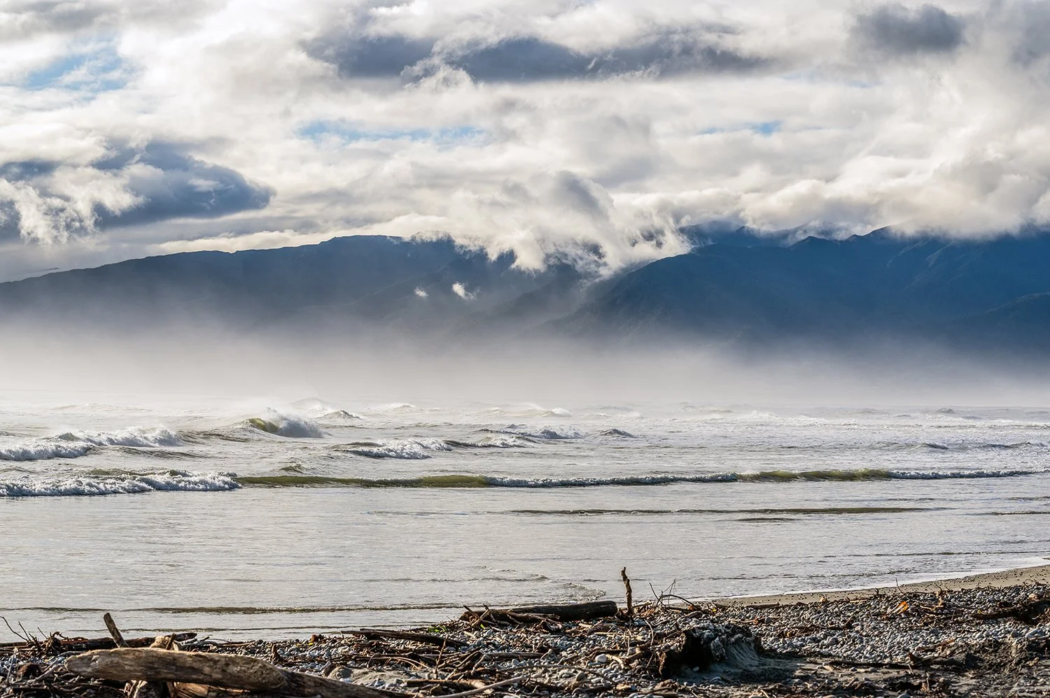 Layered mountain ranges fading into soft light beside the coast.
