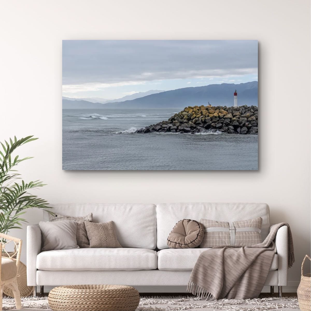 Beacon on a rocky breakwater with mountains beyond on New Zealand's West Coast.