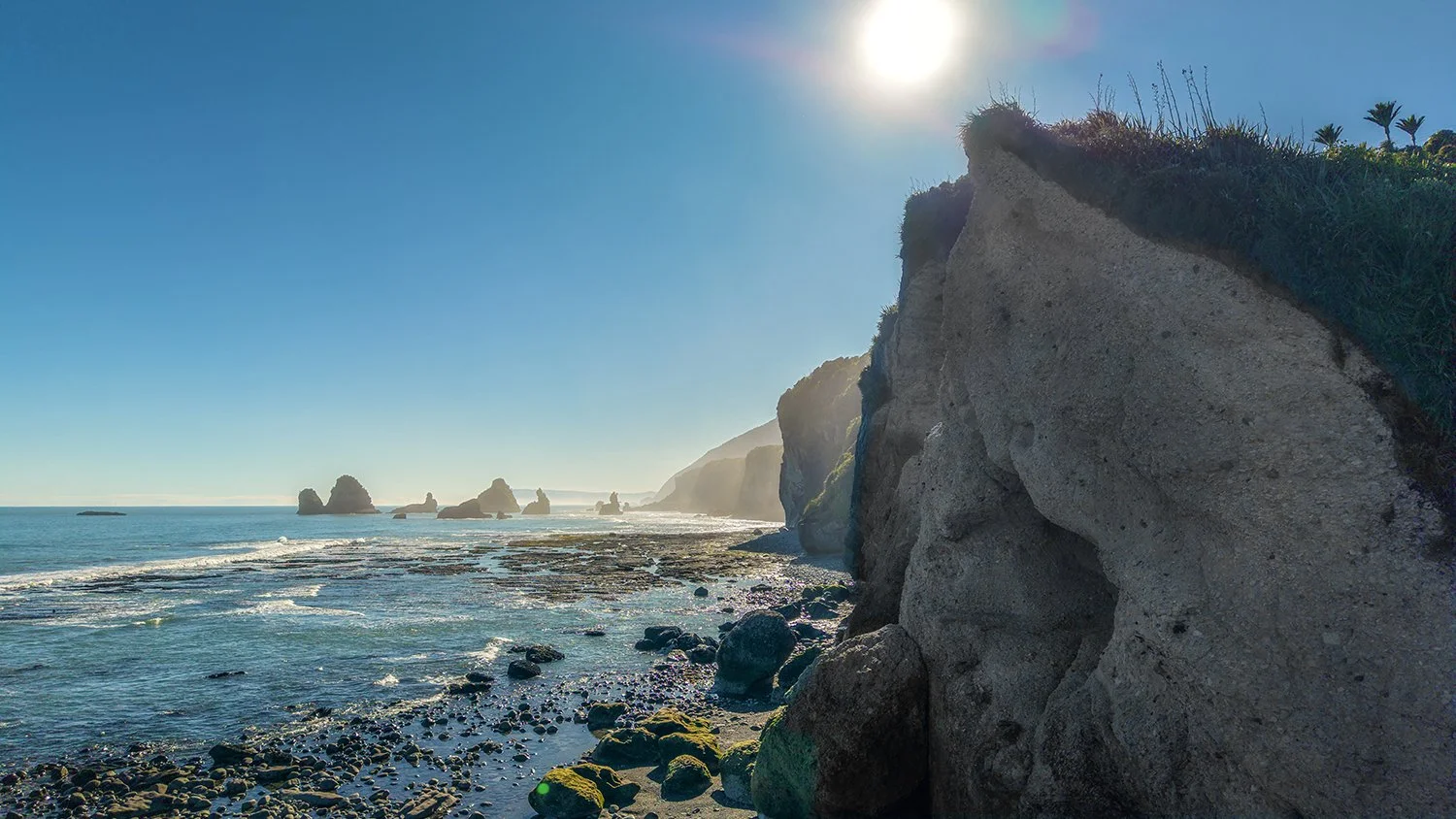 Rugged coastline with cliffs, sea stacks and rocky shoreline.