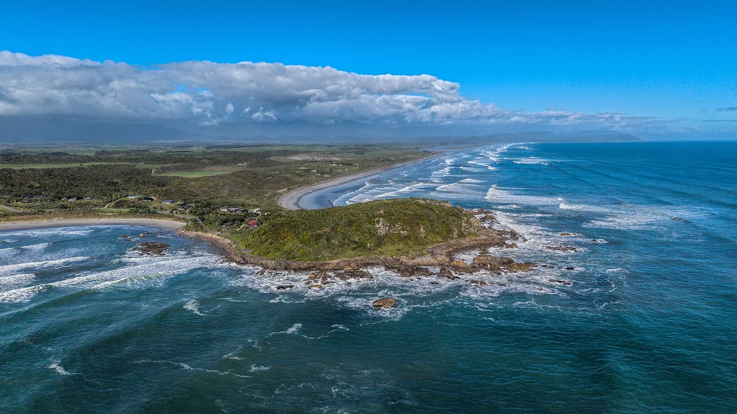Aerial view of rugged West Coast shoreline and rolling ocean waves.