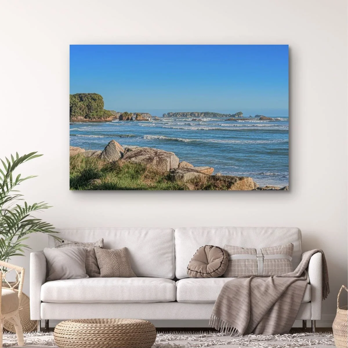 Waves rolling towards rocky coastline beneath blue skies on the West Coast of New Zealand.