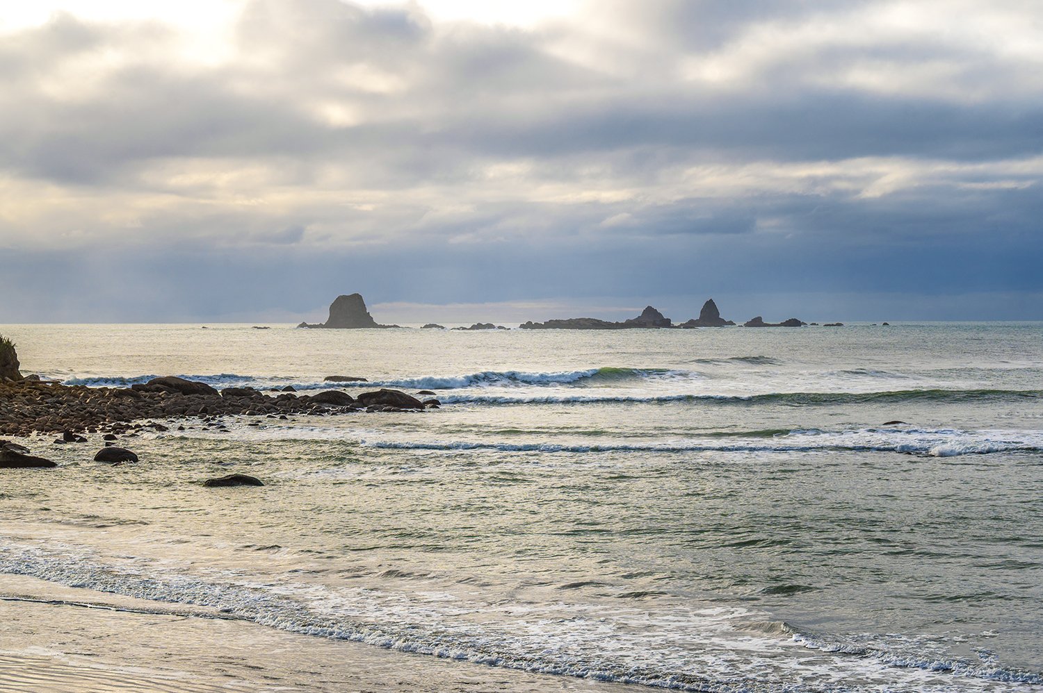 Sunlight returning across wet beach reflections on the West Coast.