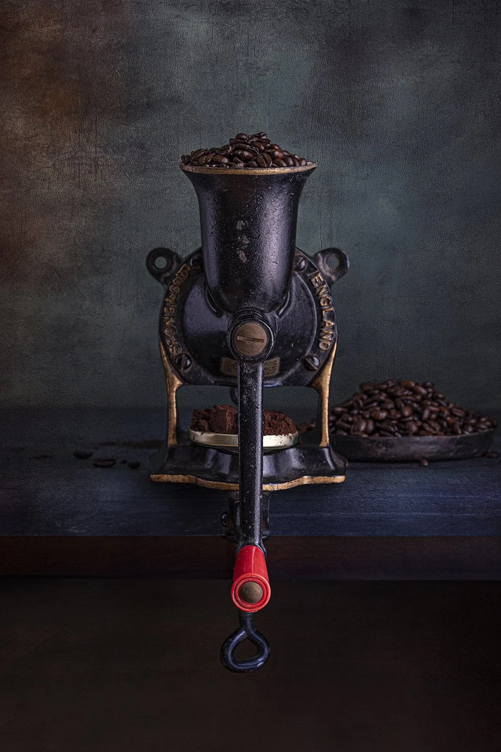 Vintage coffee grinder filled with roasted coffee beans.