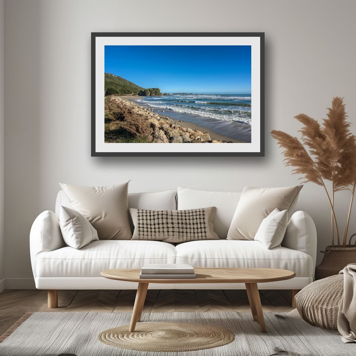 Waves rolling onto a rocky West Coast beach with distant sea stacks beneath a clear blue sky.