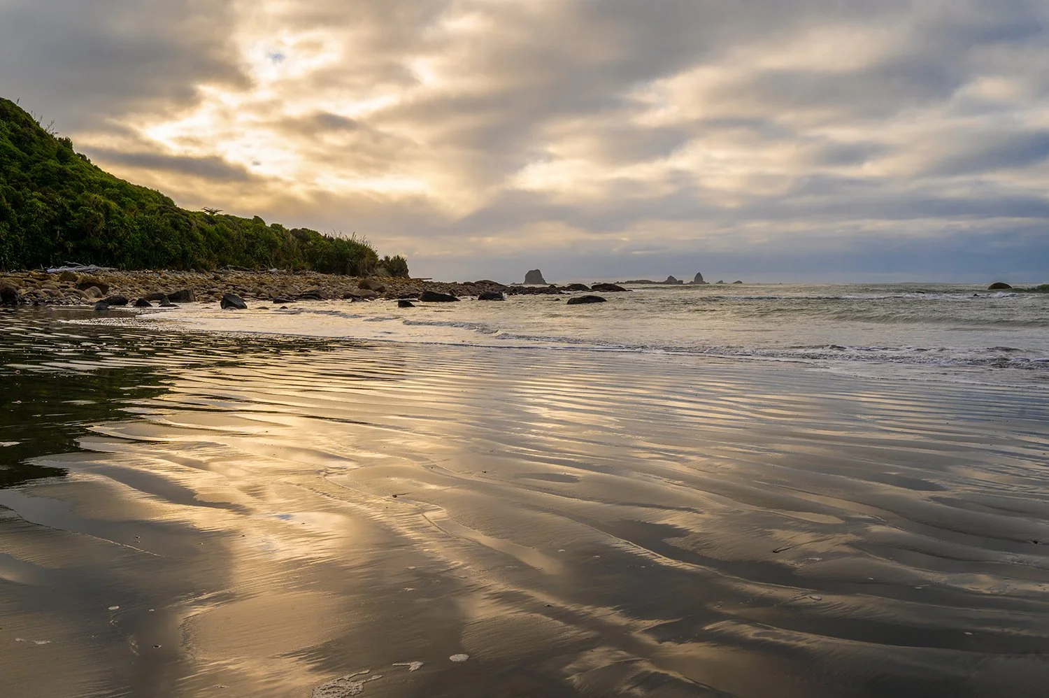 Golden light reflected across rippled beach sand on the West Coast.