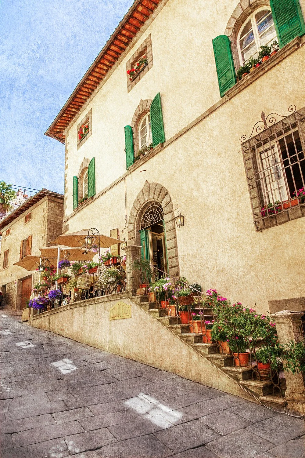 Italian building entrance with flowers, shutters and stone architecture.