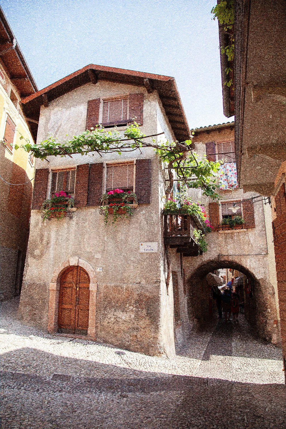 Historic Italian laneway with balconies, flowers and stone archways.