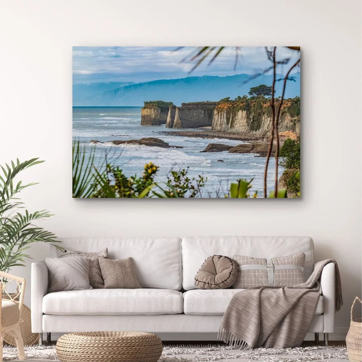 Native coastal plants framing limestone cliffs and the Tasman Sea on New Zealand's West Coast.