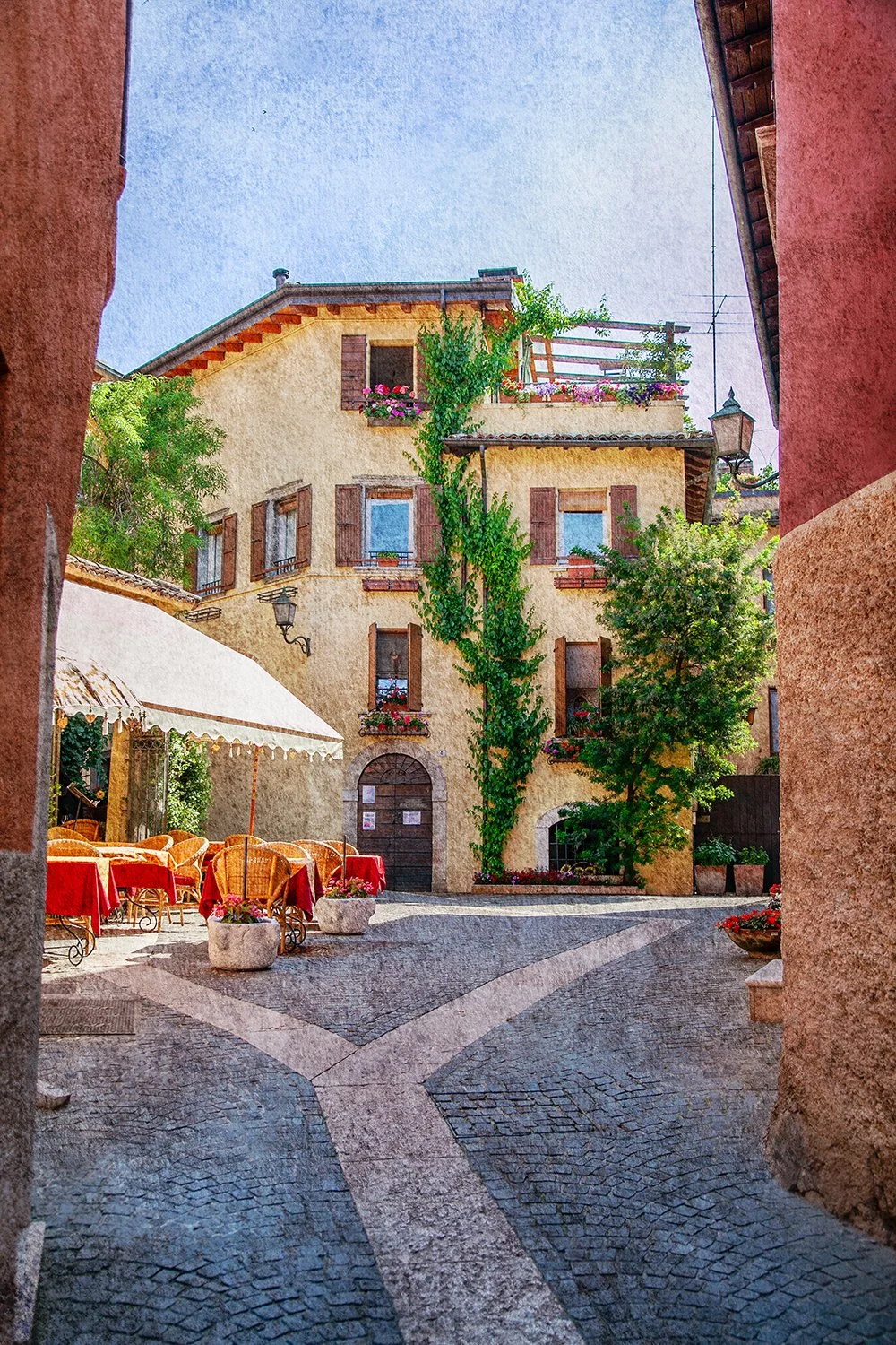 Italian terrace framed by historic buildings and flowers.