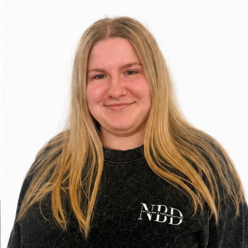 A young woman with long blonde hair smiling, wearing a black shirt with white text on it, against a plain white background.