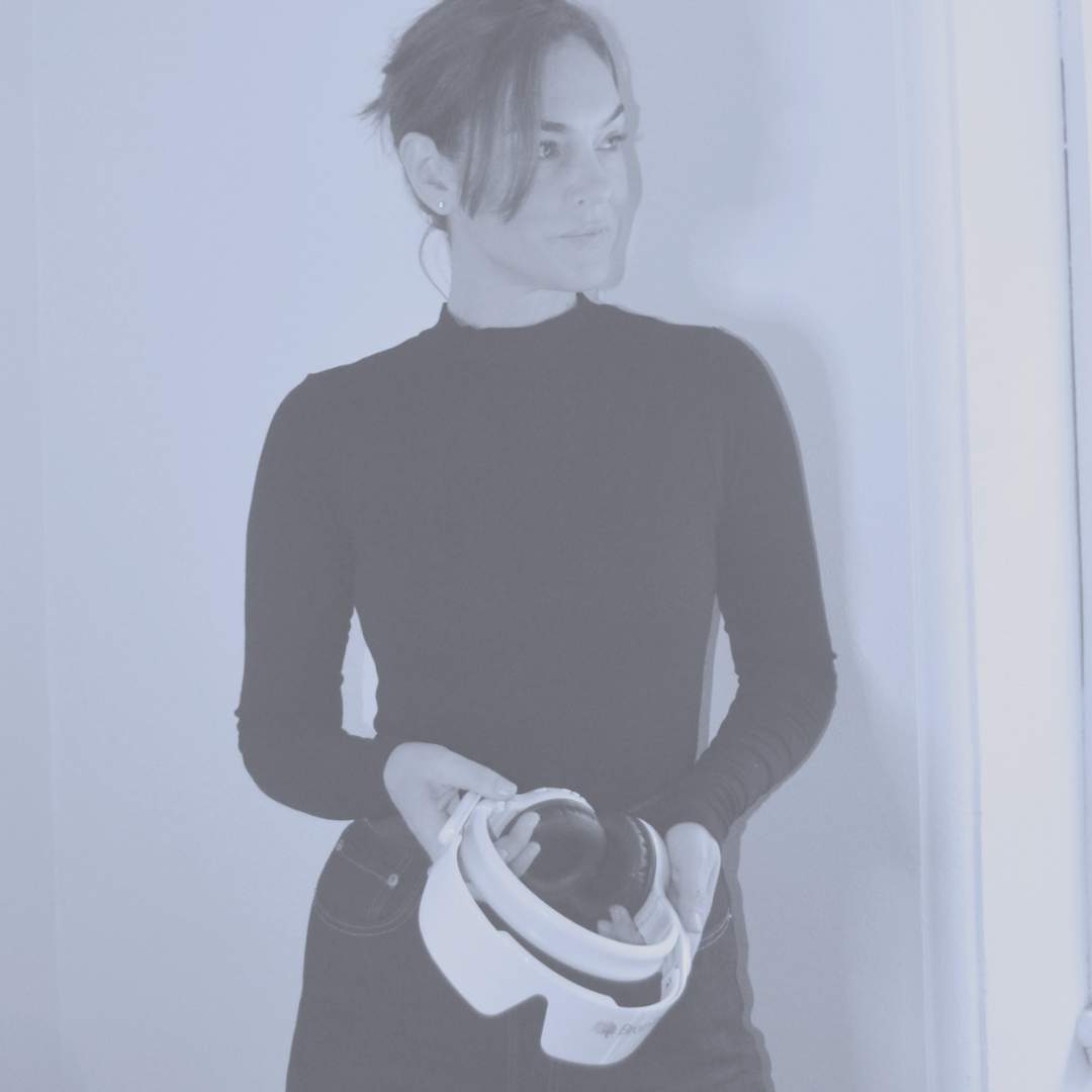 Woman holding a virtual reality headset, standing indoors.