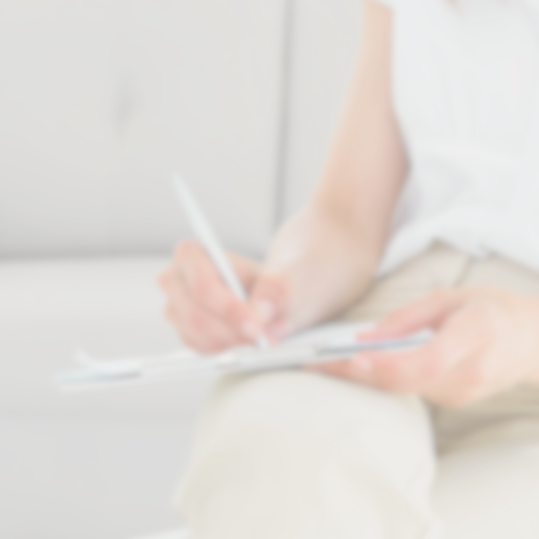 Blurred image of a person writing with a pen on a notepad.