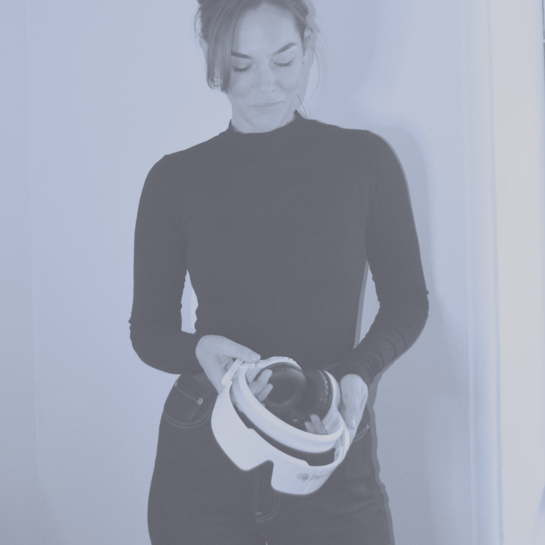 Woman in black long-sleeve shirt holding a white virtual reality headset.
