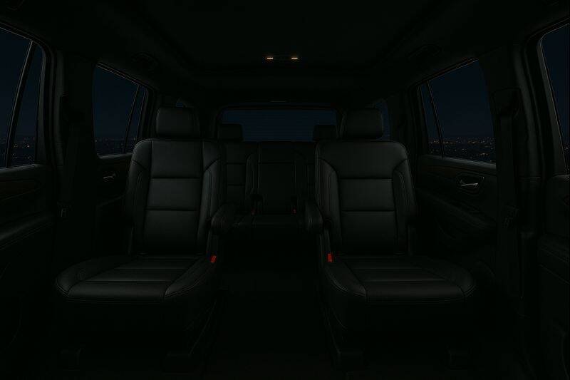 Dark interior of an SUV with black leather seats and windows showing a night cityscape.