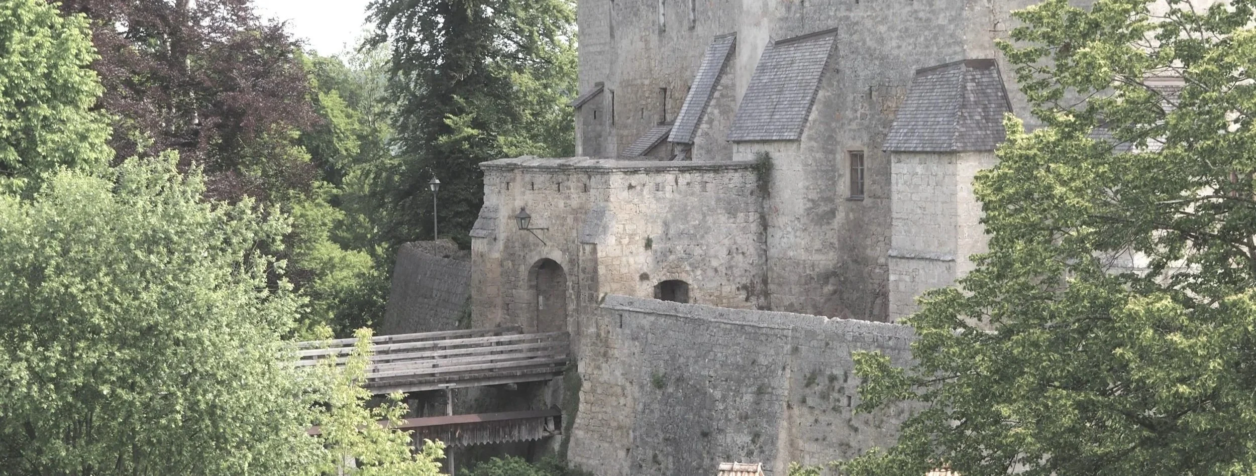 Historisches Stein-Gebäude mit Brücke im Grünen, Bäume und Fenster