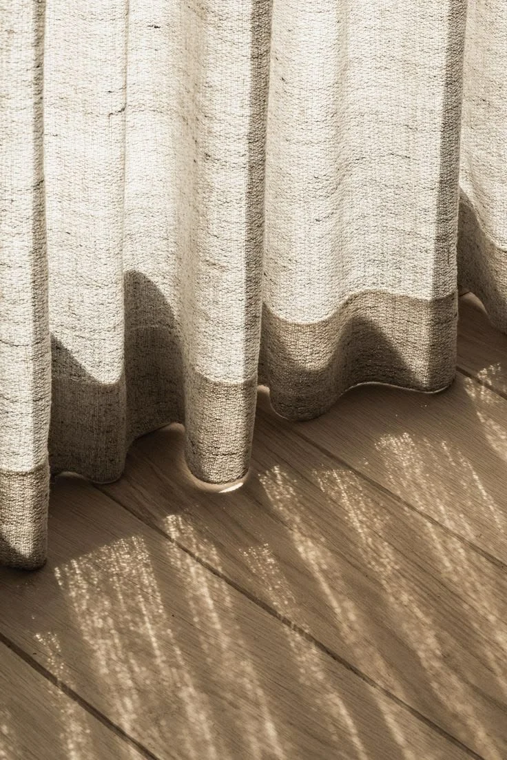 Sunlight passing through a curtain, casting circular patterns on wooden floor.