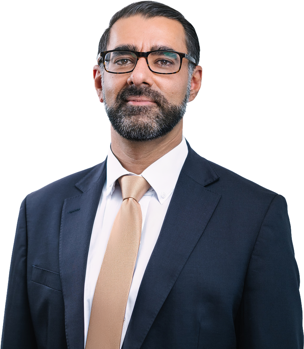 A professional man wearing glasses, a dark suit, white shirt, and a beige tie, looking confidently at the camera.