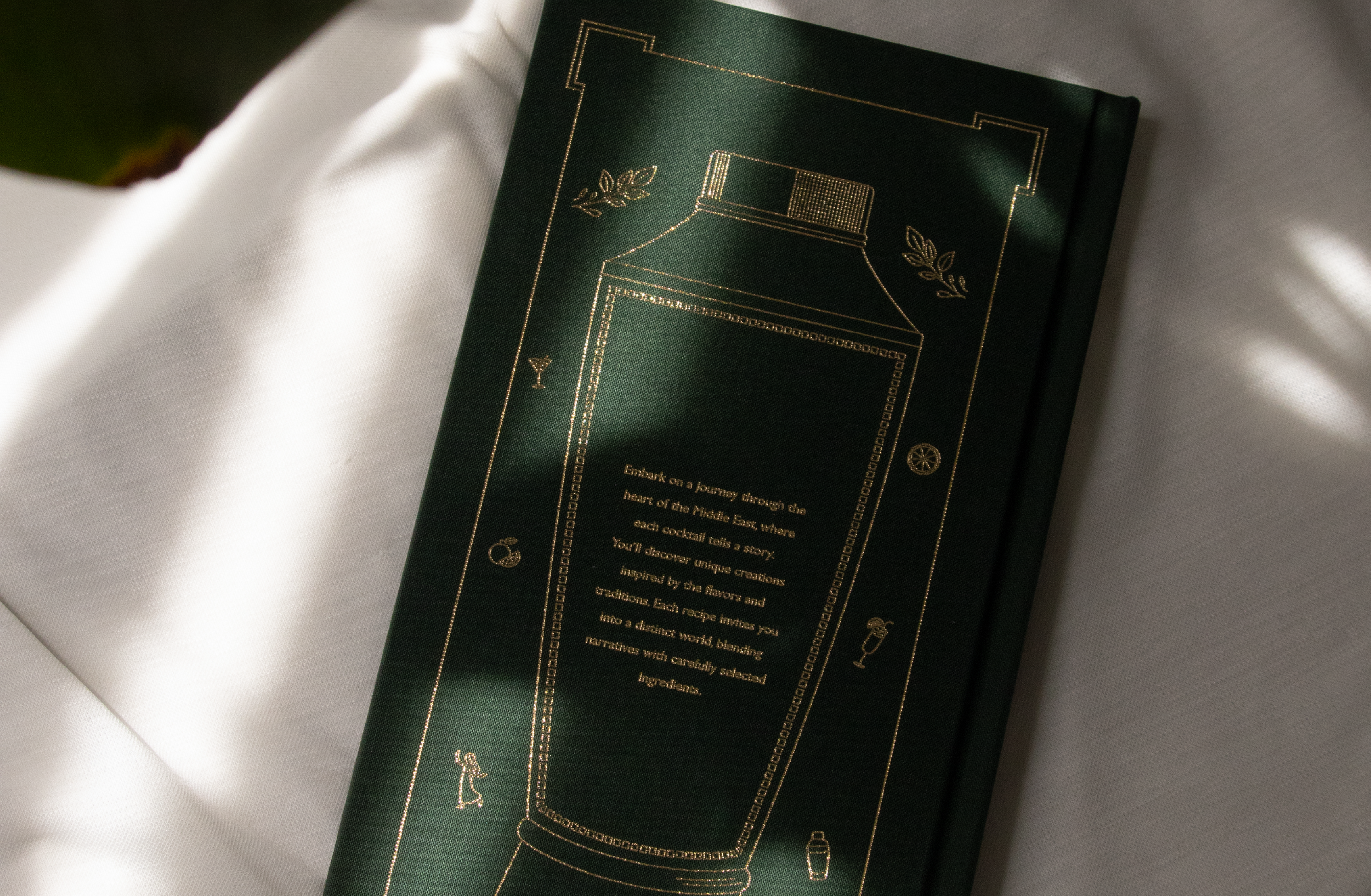 Une brochure verte avec un design doré, posée sur une surface blanche. Elle comporte un dessin doré d'un robot ou d'une machine, avec du texte en dessous. La brochure semble promouvoir une expérience ou un produit lié à la technologie ou à une aventure.