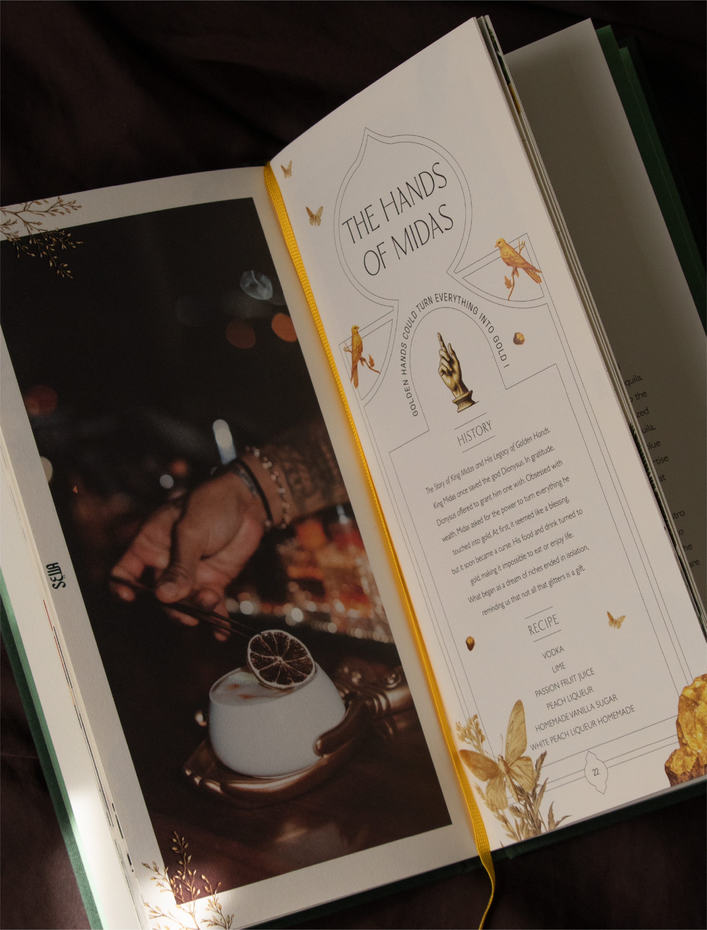 Une page d'un livre avec un titre en anglais "The Hands of Midas" et une illustration d'une main pointant vers le haut, entourée de petits oiseaux et de motifs floraux. La page contient aussi du texte en anglais et une section intitulée "RECIPES".