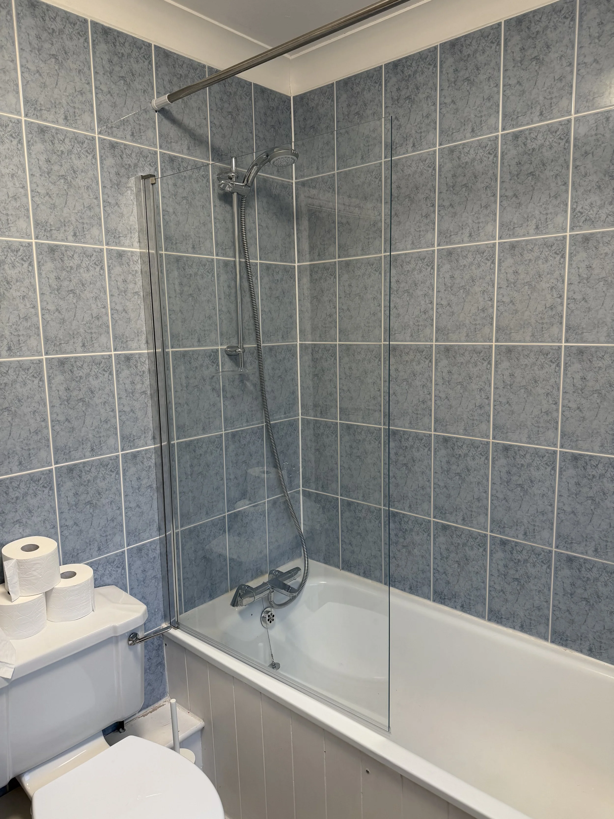 A new shower screen installed on a bath in a bathroom.