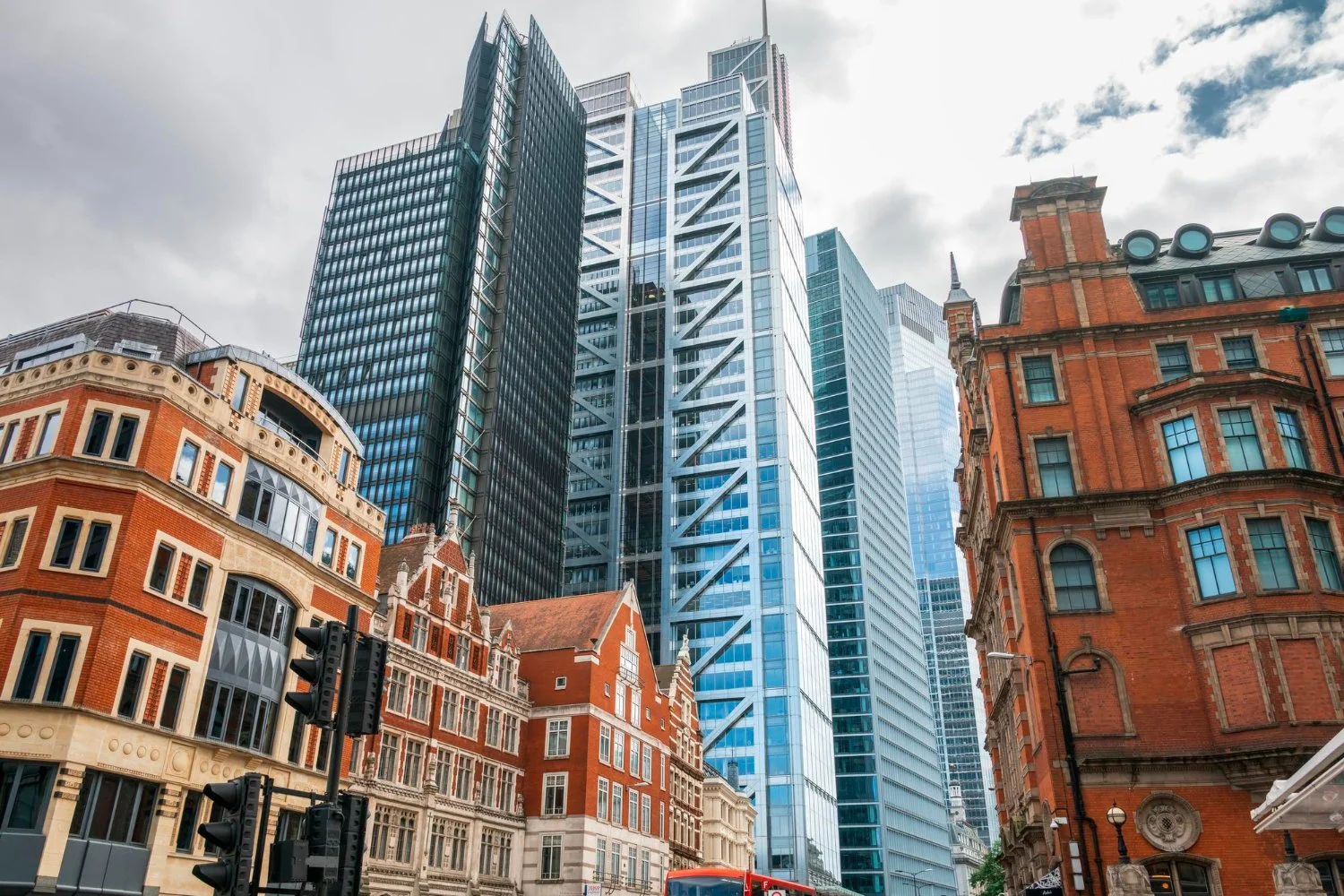 A cityscape featuring tall modern glass skyscrapers alongside historic red brick buildings with ornate details, captured from street level.