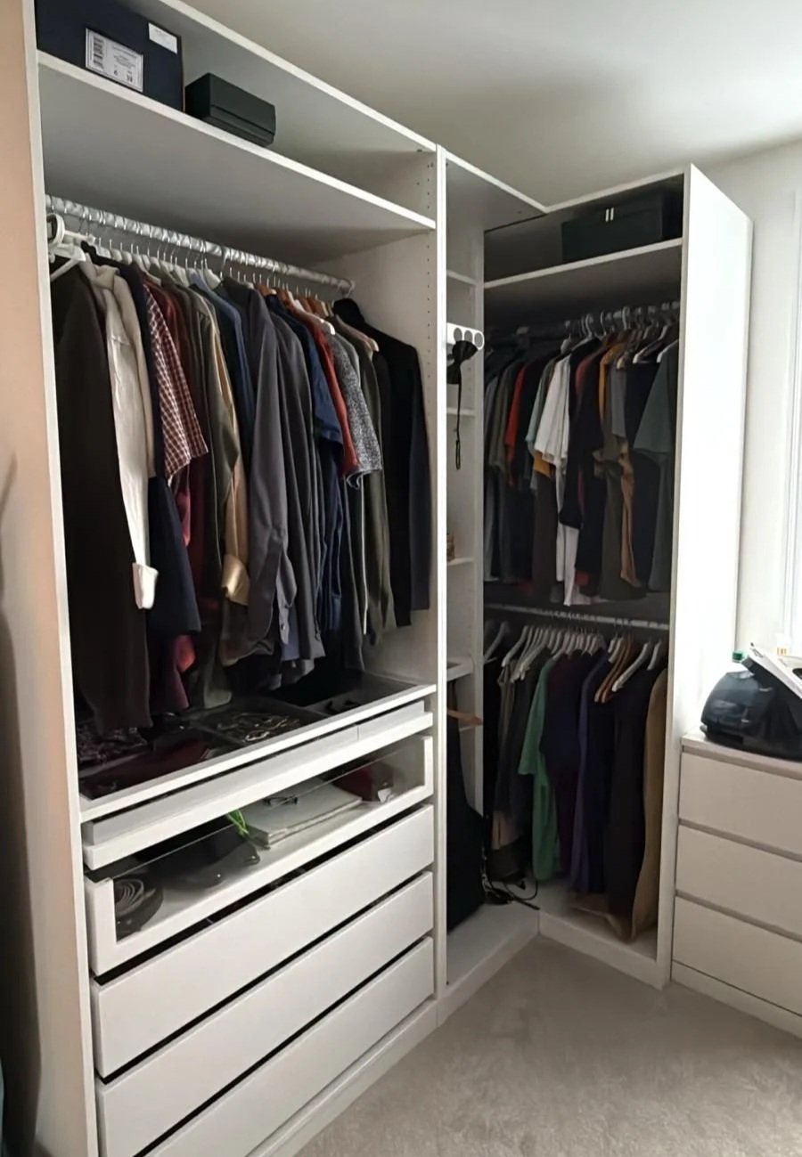 A walk-in closet installed with white shelves and drawers and metallic rails.