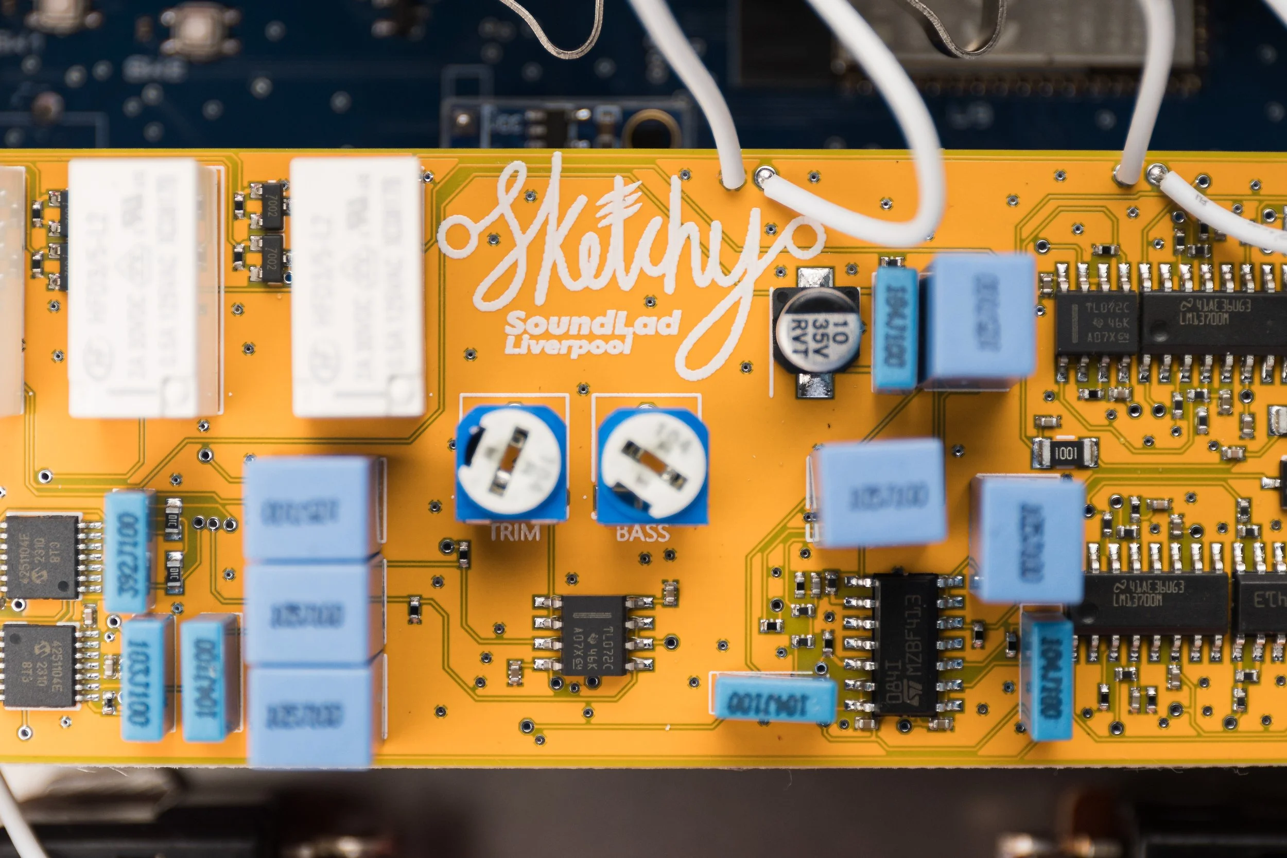 Close-up of a yellow electronic circuit board with various blue and black components, including capacitors and resistors, with the logo 'sketchy Sound Lab Liverpool' in white text.
