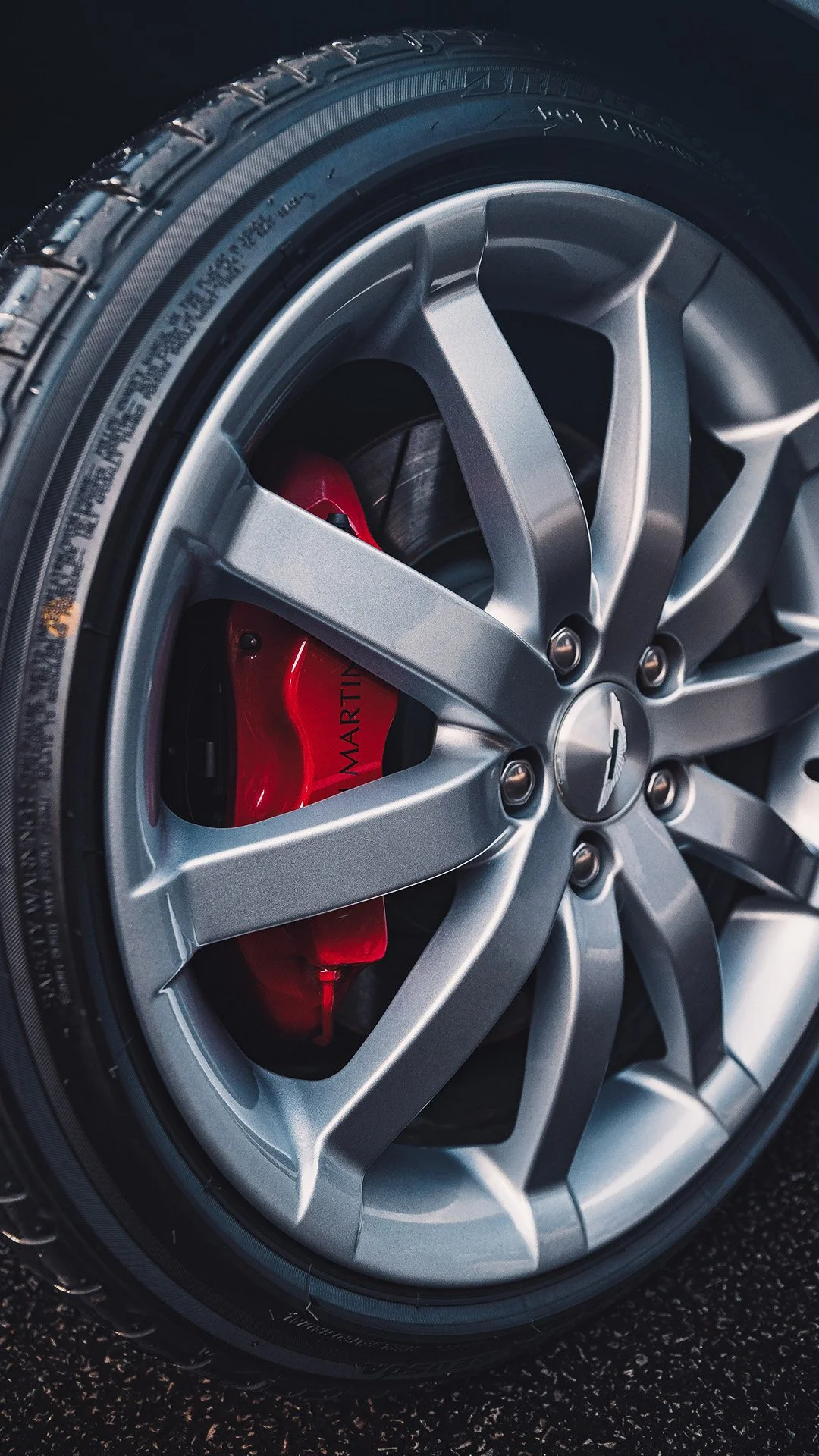 Close-up of a silver car wheel with a red brake caliper visible through the spokes.