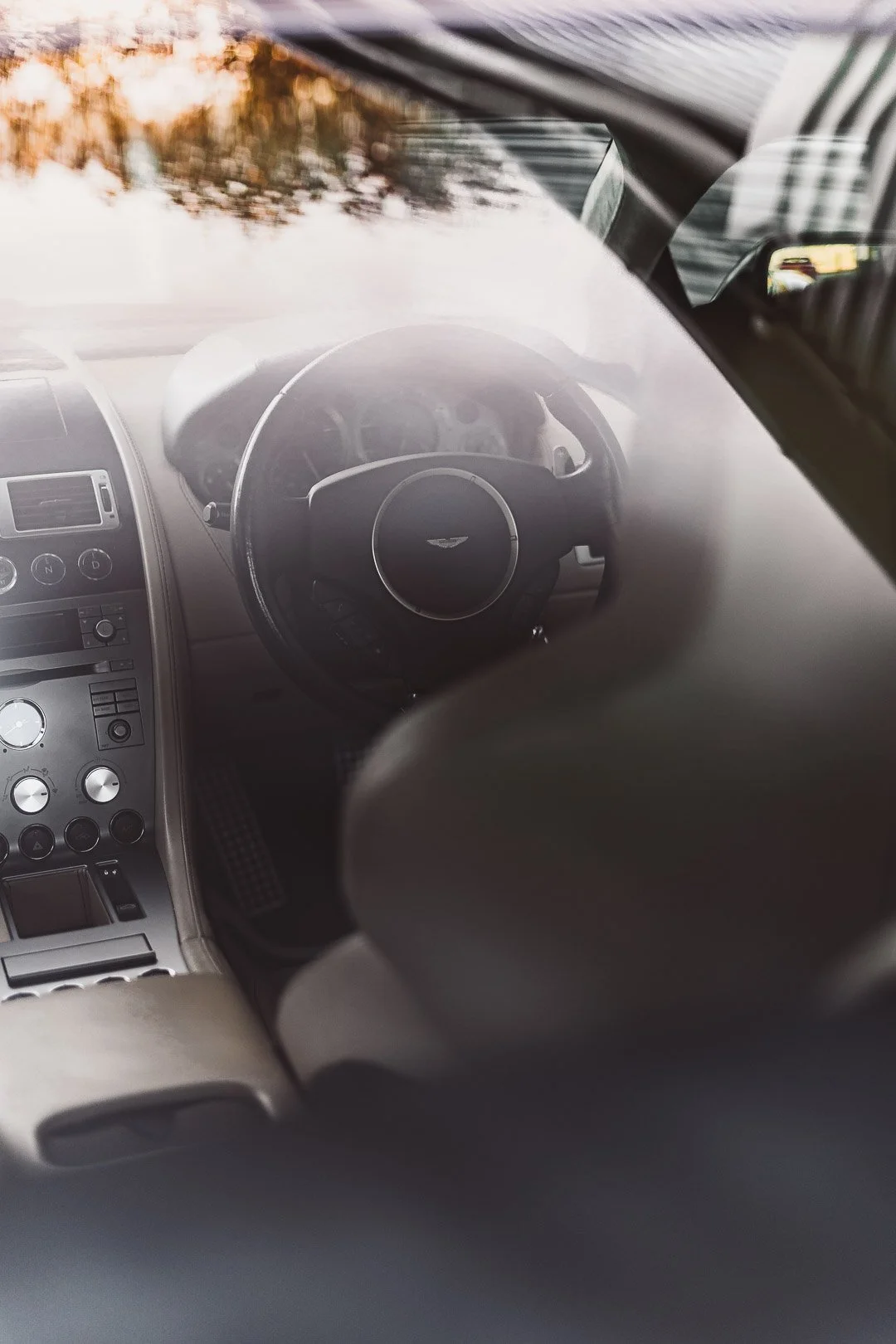 Interior view of a car, focusing on the dashboard and steering wheel, seen through a partially foggy or smudged windshield.