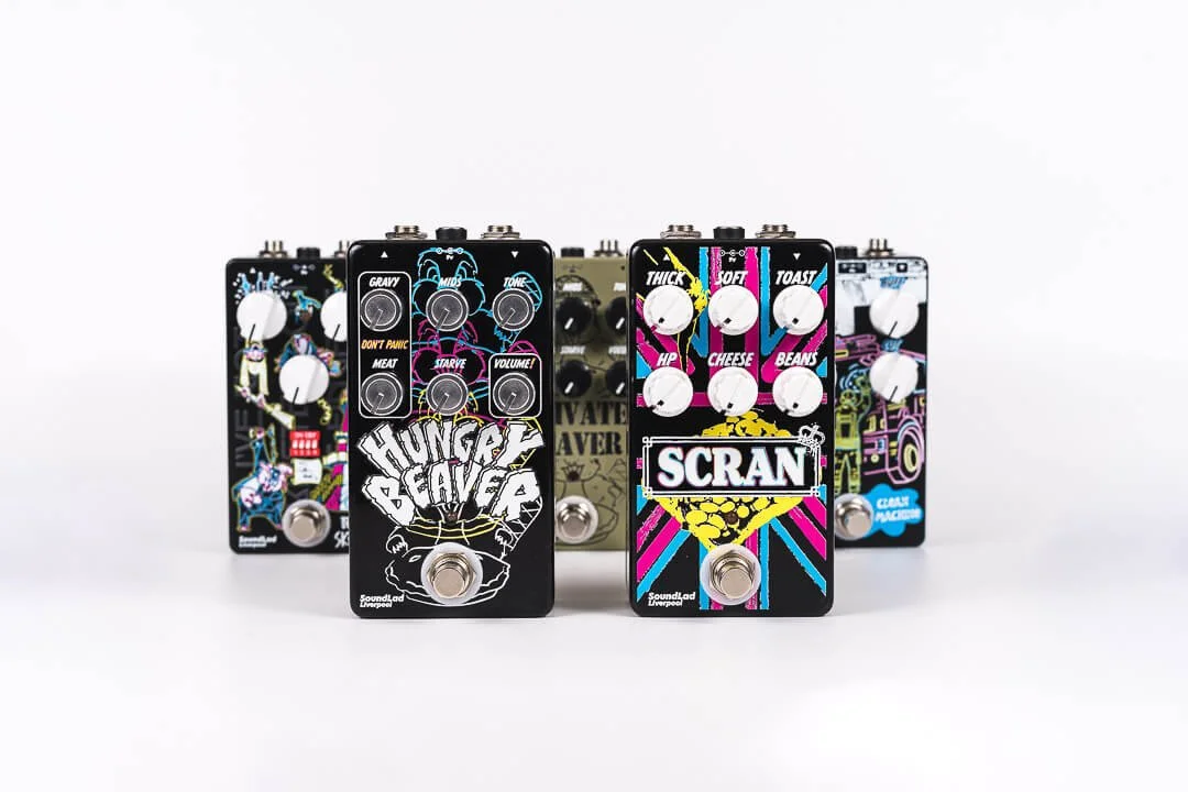 Six colorful guitar effect pedals with graffiti-style artwork and white knobs, arranged in a row on a white background.