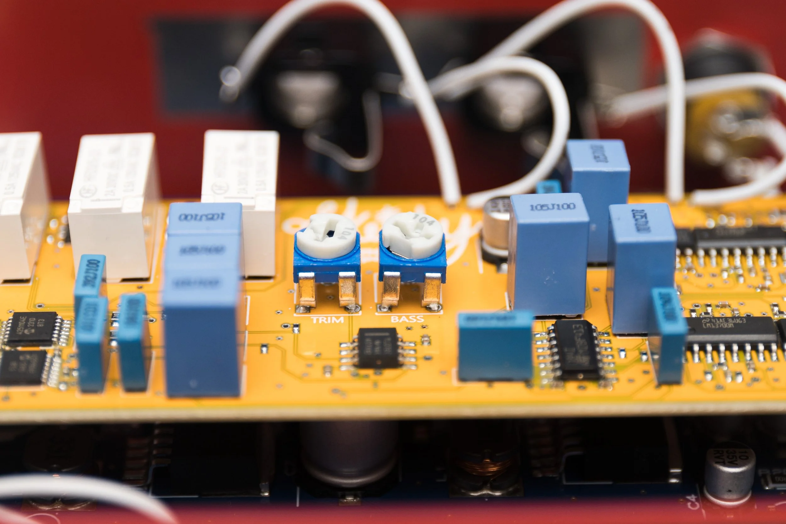 Close-up of a yellow electronic circuit board with various blue and white components, including capacitors, resistors, and connectors.
