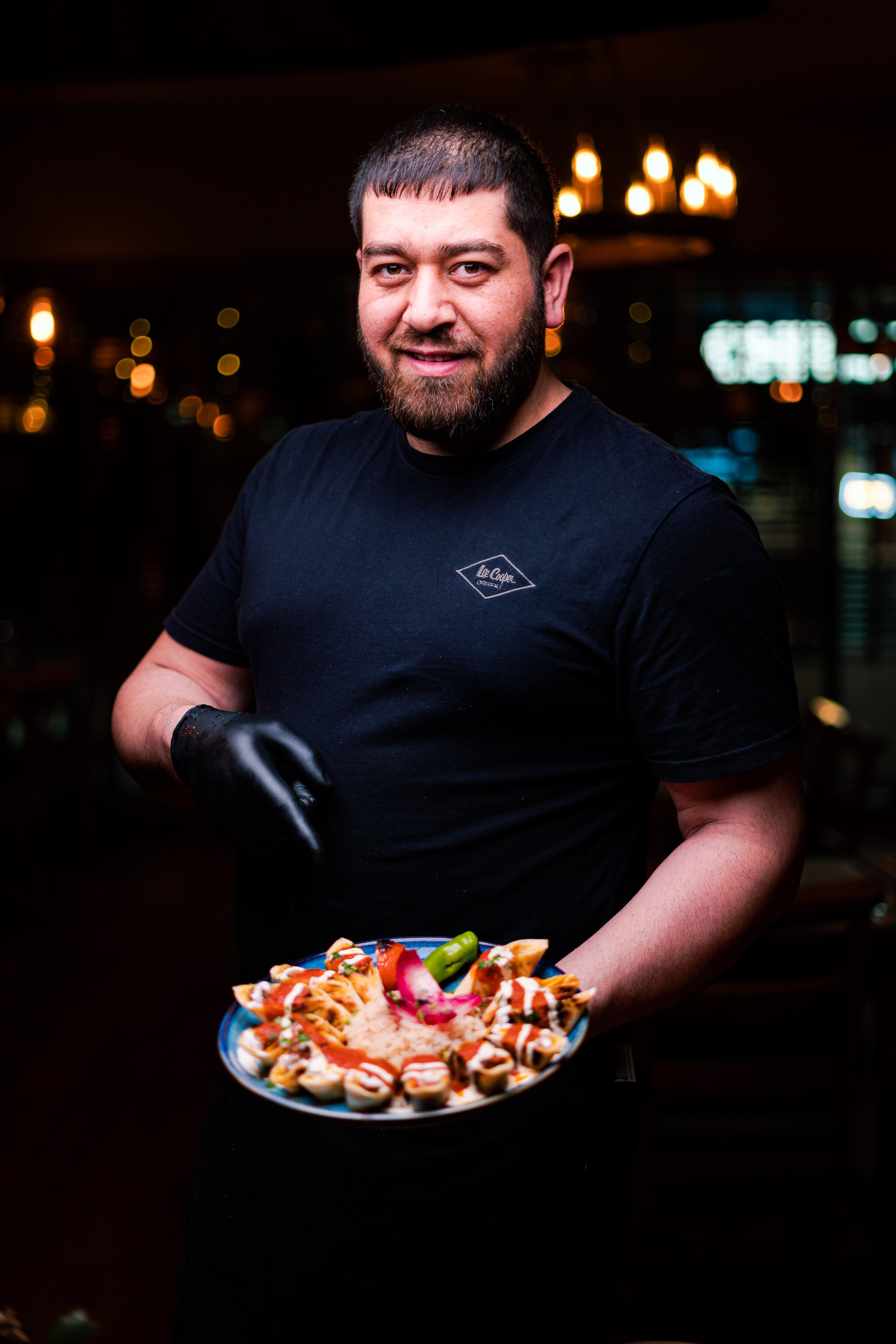 A man holding a plate of sushi in a dimly lit restaurant