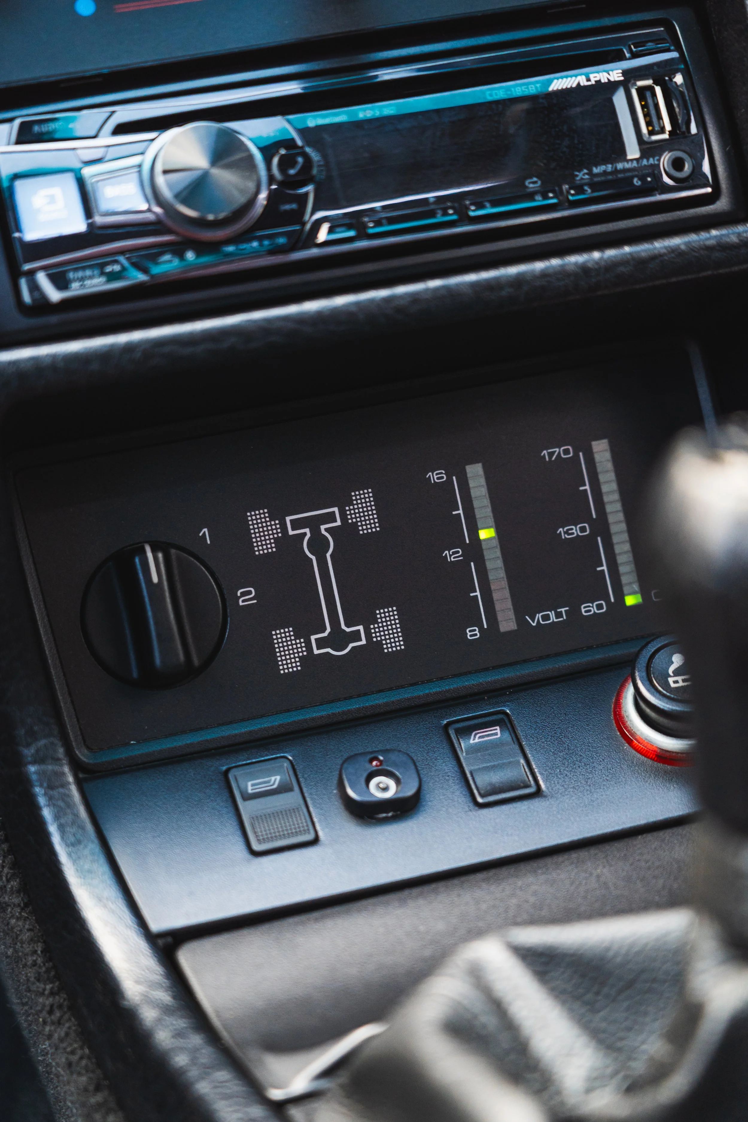 Close-up of a vehicle's dashboard showing a tire pressure monitoring display, voltage meter, and various controls, with an aftermarket Alpine stereo system above.