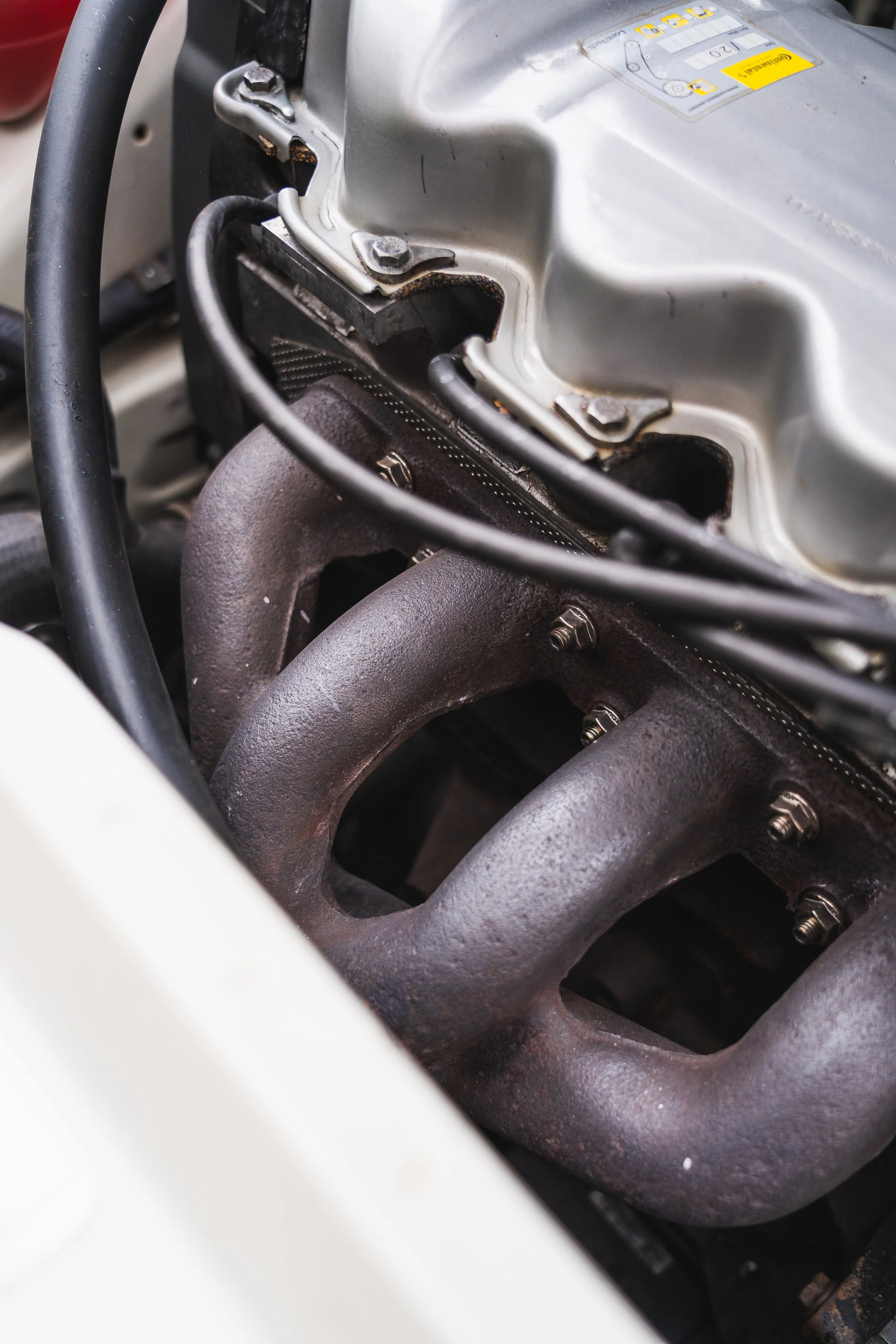 Close-up of a car engine showing rusty exhaust manifolds and part of the engine block.