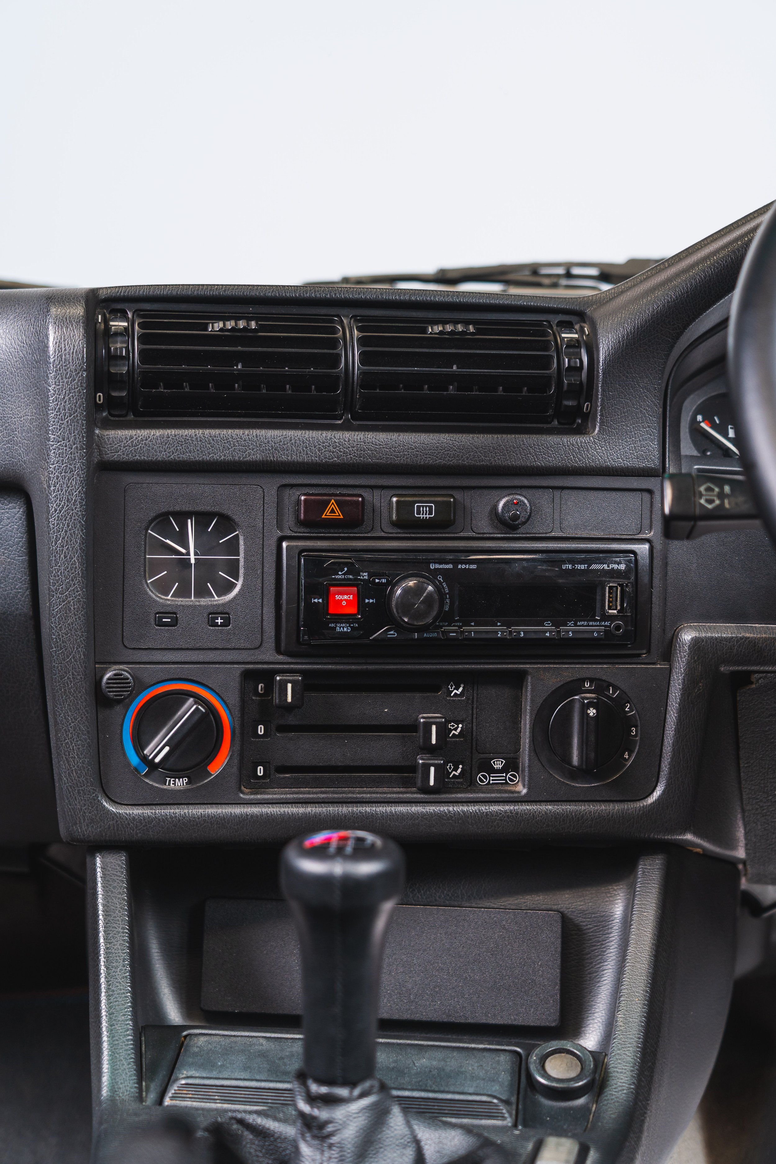 Interior of a vehicle dashboard with air vents, radio, clock, and temperature controls.