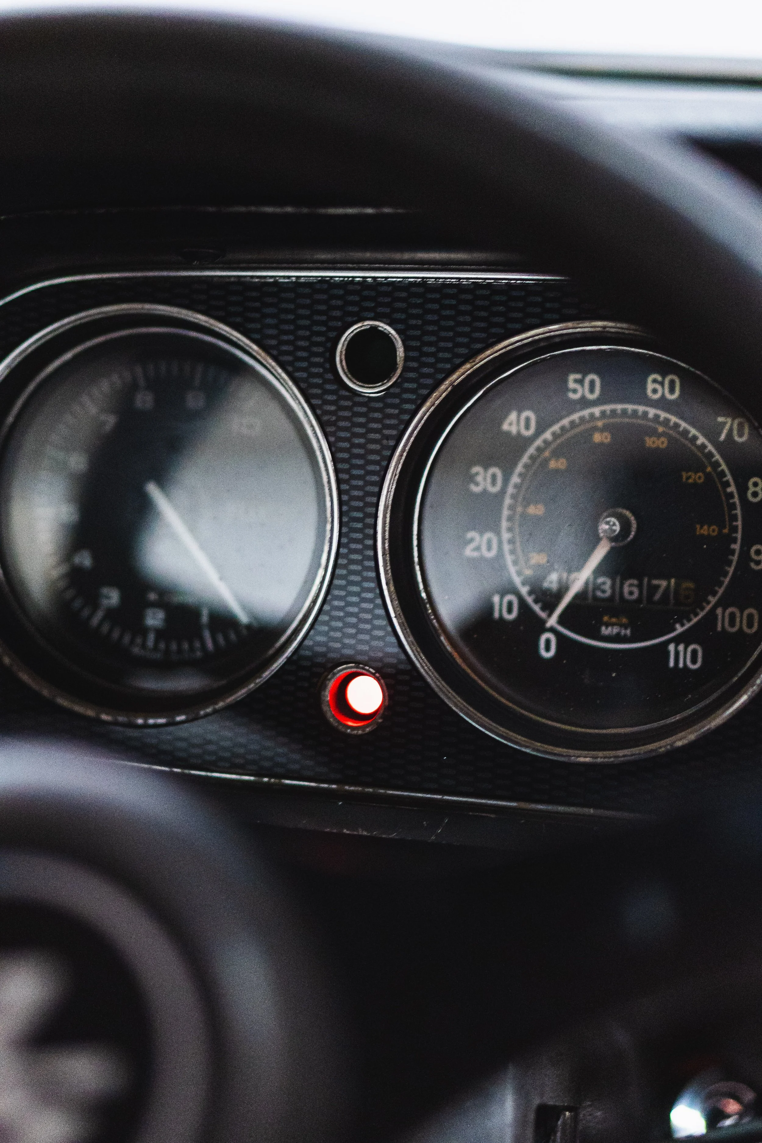 Close-up of a car dashboard with speedometer showing 36 mph and an illuminated red warning light.
