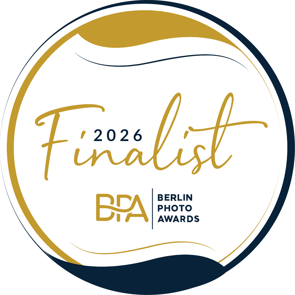 Circular logo for the 2026 Berlin Photo Awards Finalist with gold and dark blue accents, featuring the texts "Finalist 2026" and "Berlin Photo Awards" alongside a stylized "BPA" logo.