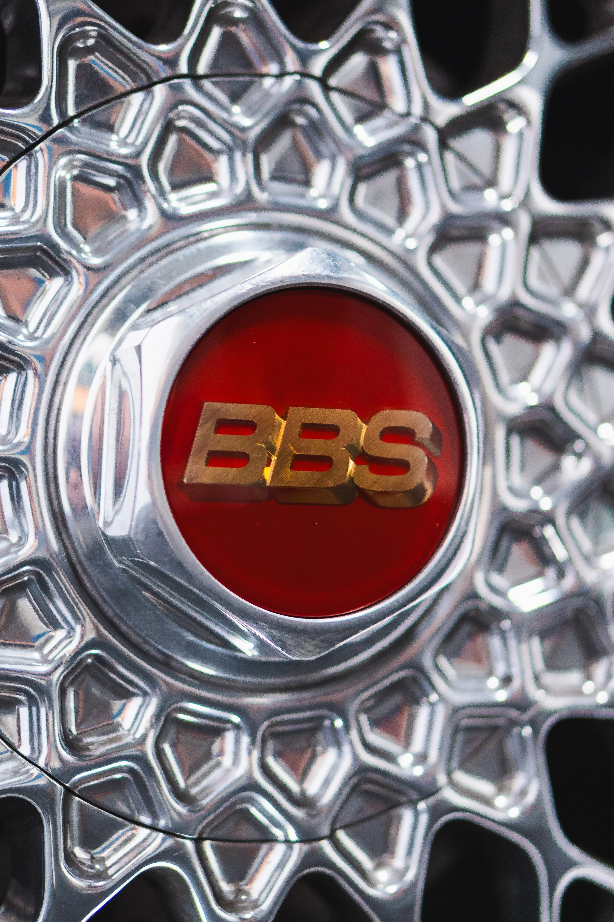 Close-up of a shiny, metallic object with a red center that has the word "BBS" in gold lettering.