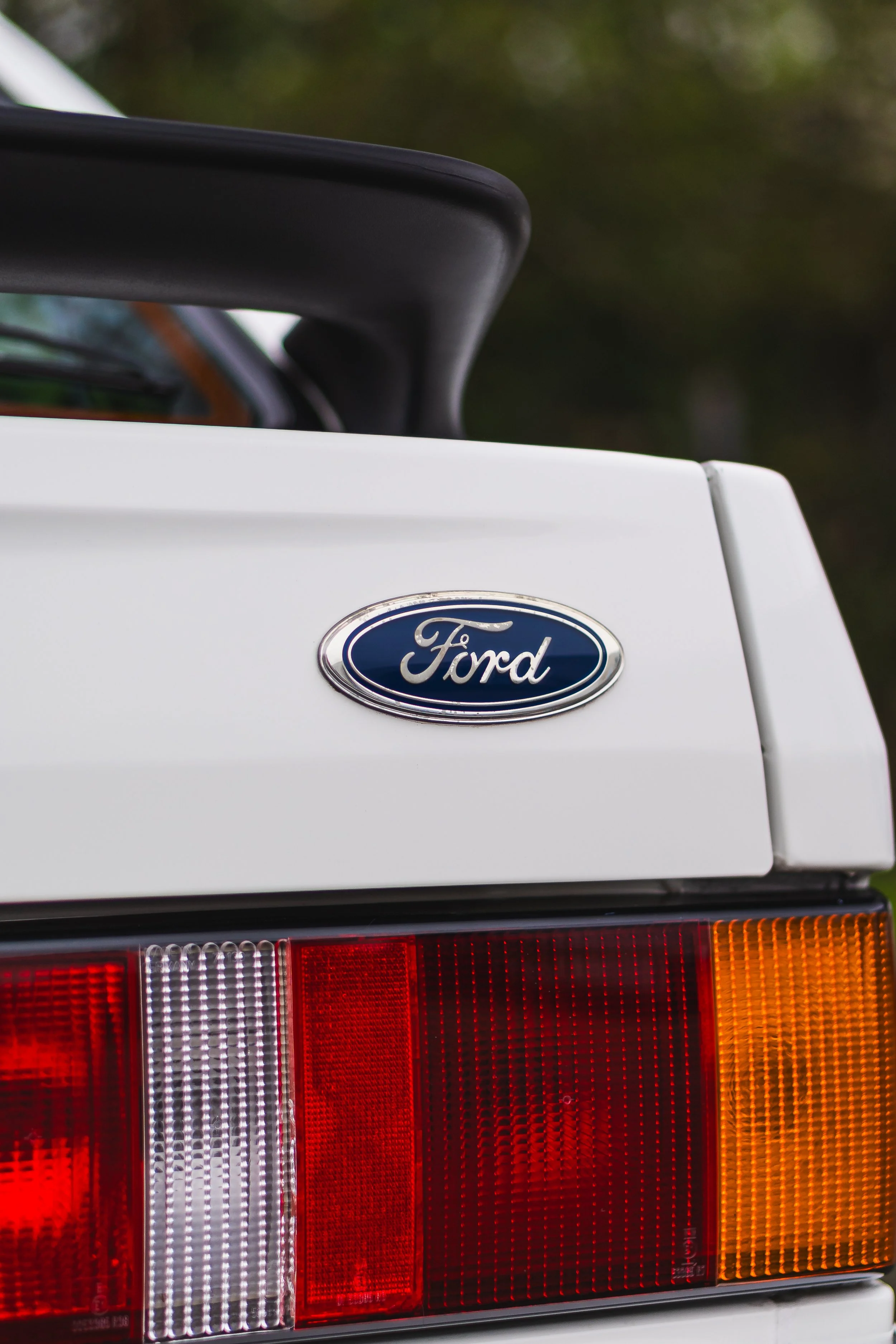 Close-up of the rear of a white Ford vehicle, showing the Ford emblem, taillights, and part of the trunk.