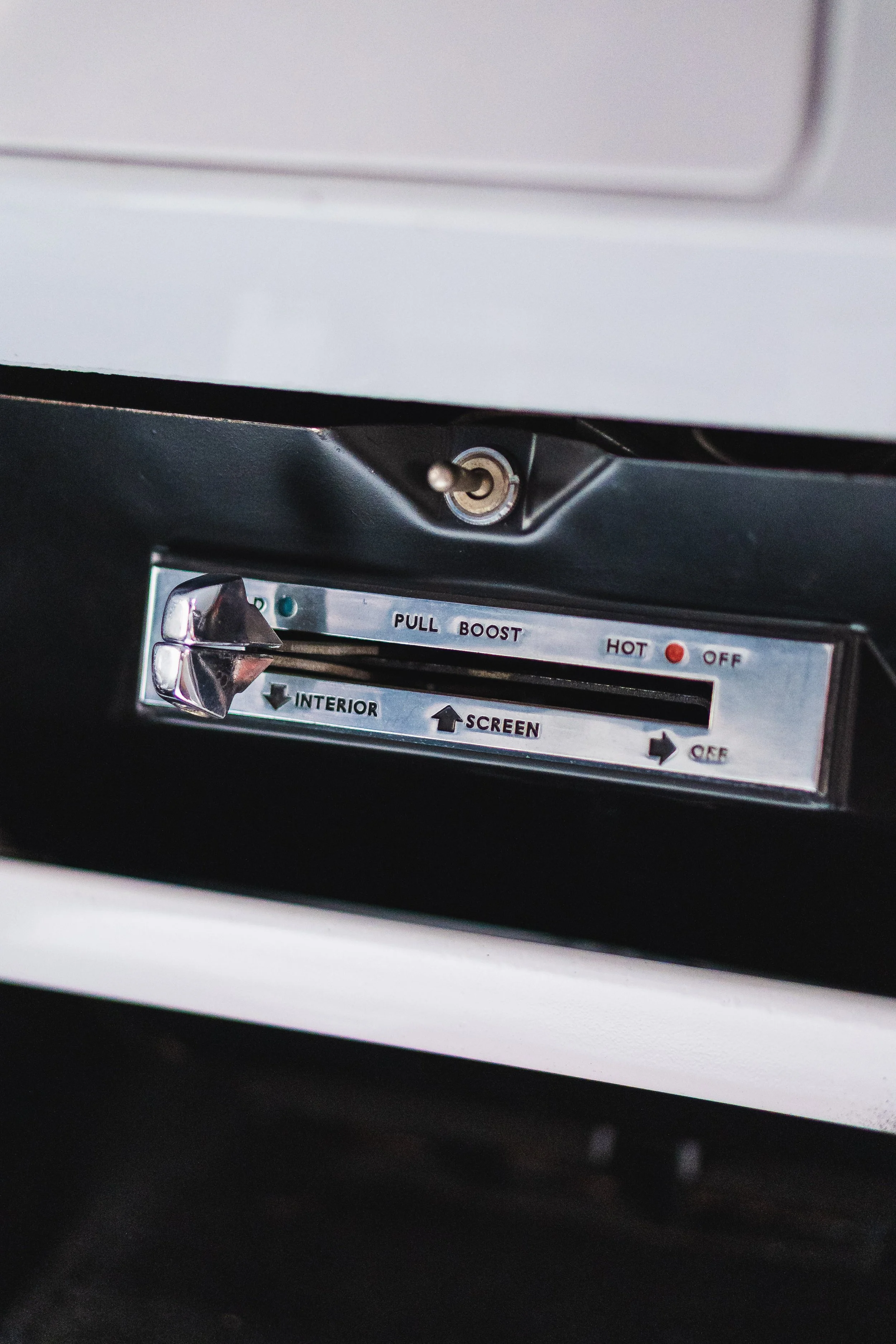 Dashboard with a vintage control panel featuring a horizontal lever labeled with settings such as 'PULL BOOST', 'HOT', 'OFF', 'INTERIOR', 'SCREEN', and arrows indicating direction.