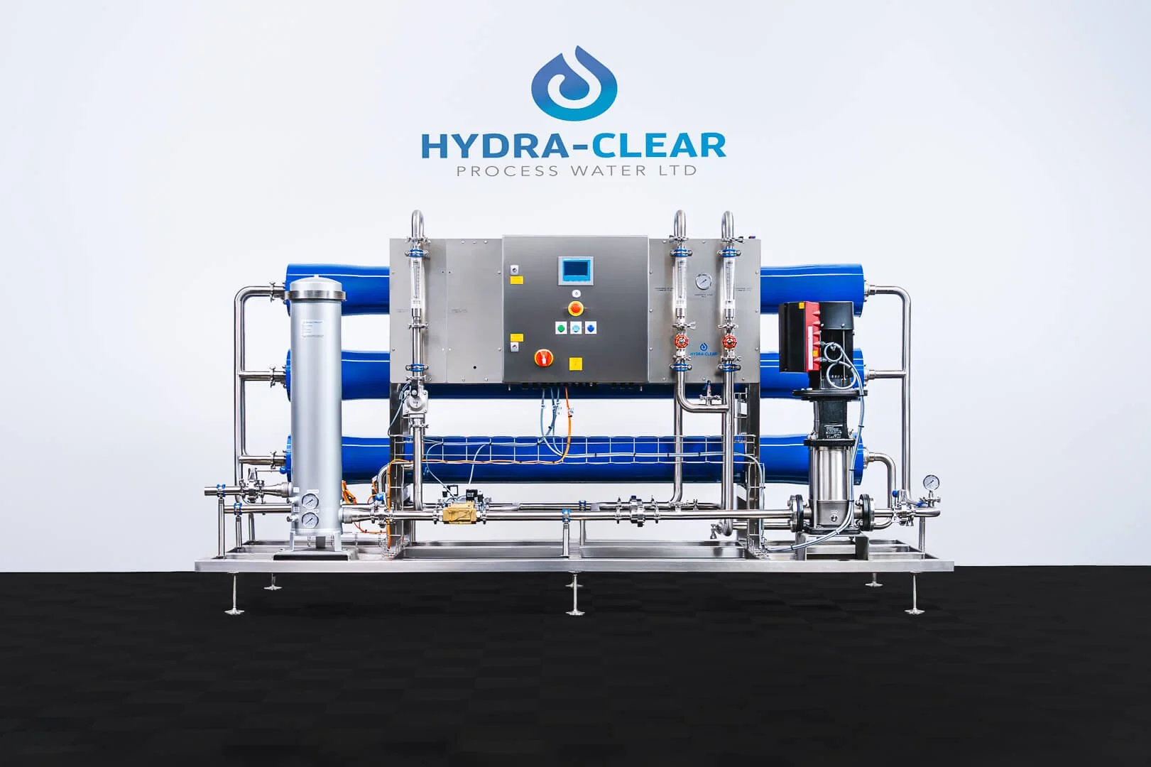 Industrial water purification machine with control panel, pipes, and blue filtration units, branded Hydra-Clear, on a black floor against a white background.