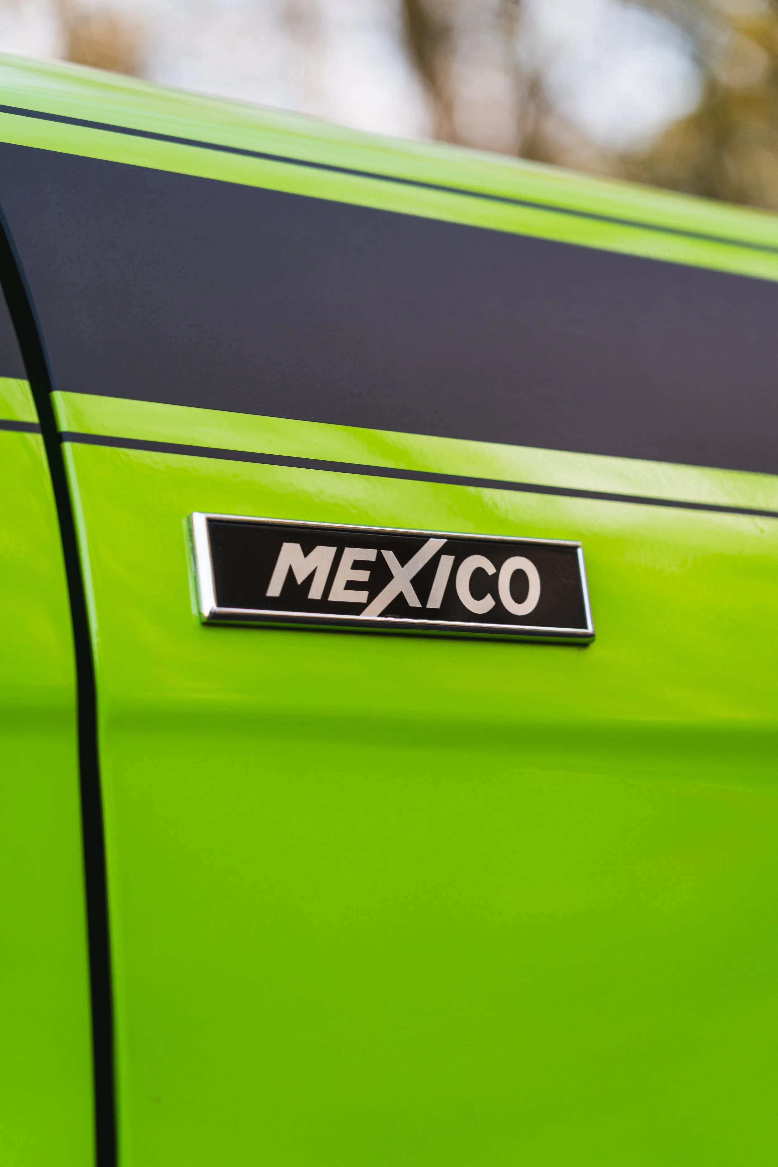 Close-up of a green vehicle with a black and silver badge that reads 'MEXICO'.