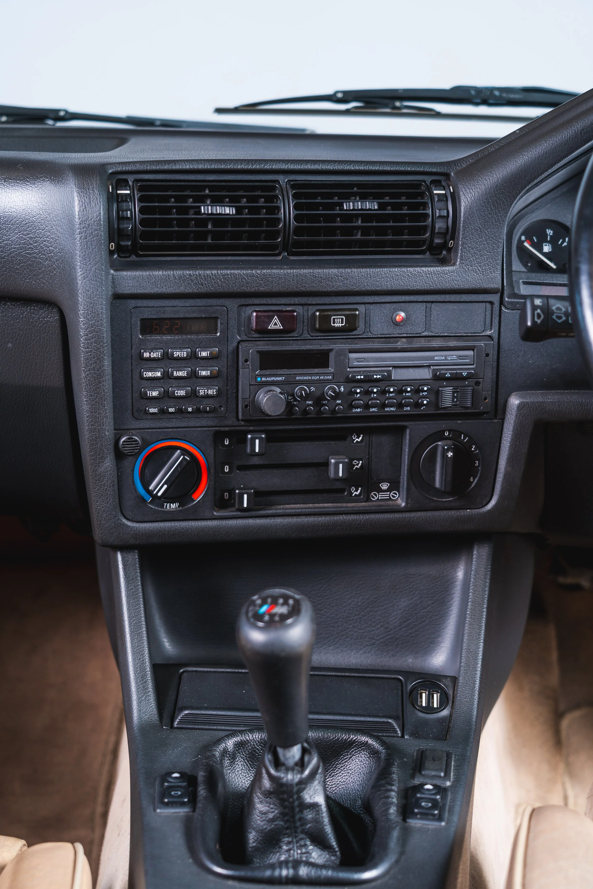 Interior view of a car dashboard with air vents, radio, climate control knobs, and gear shift in the center.