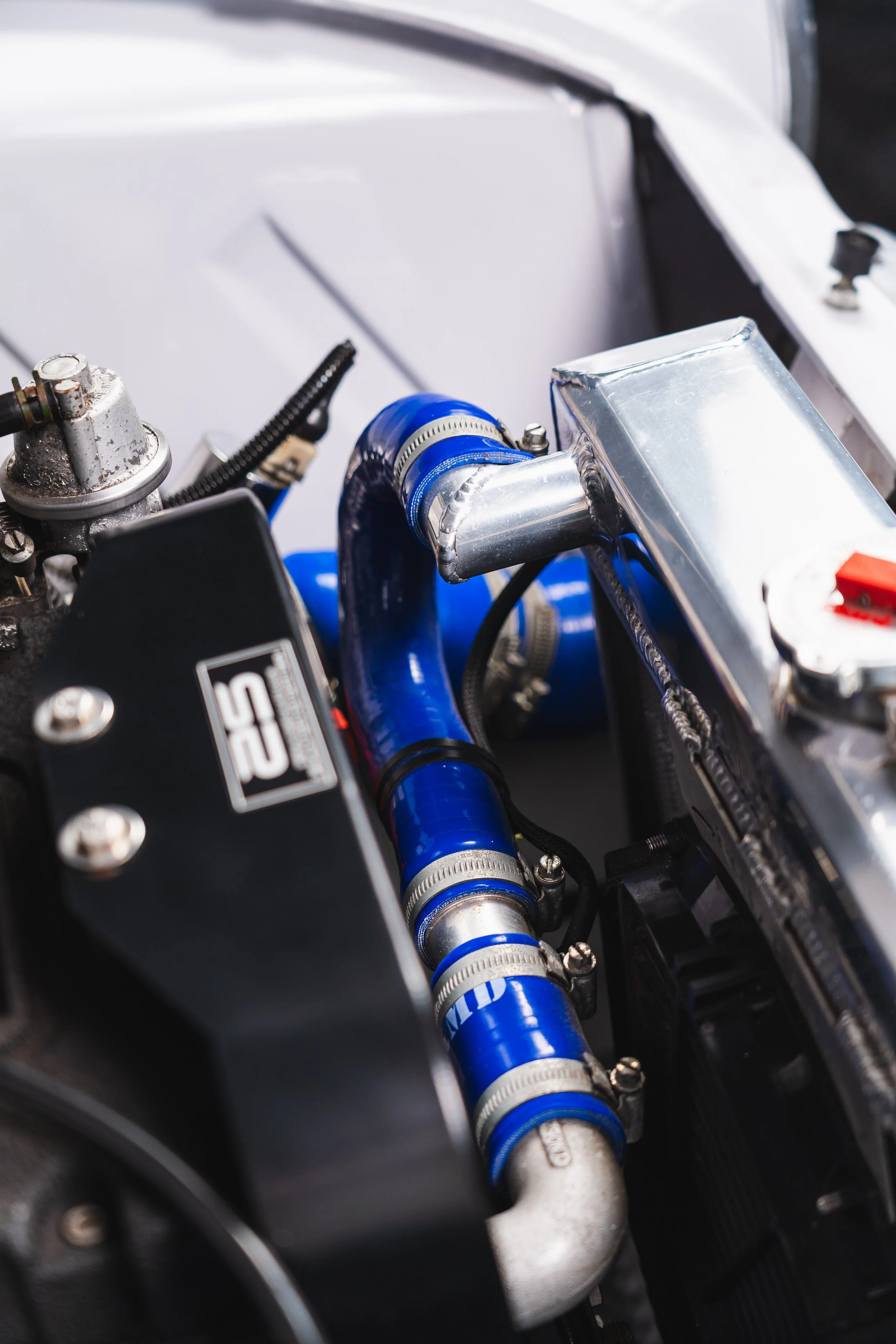 Close-up of a car engine with blue hoses, metal fittings, and black components.