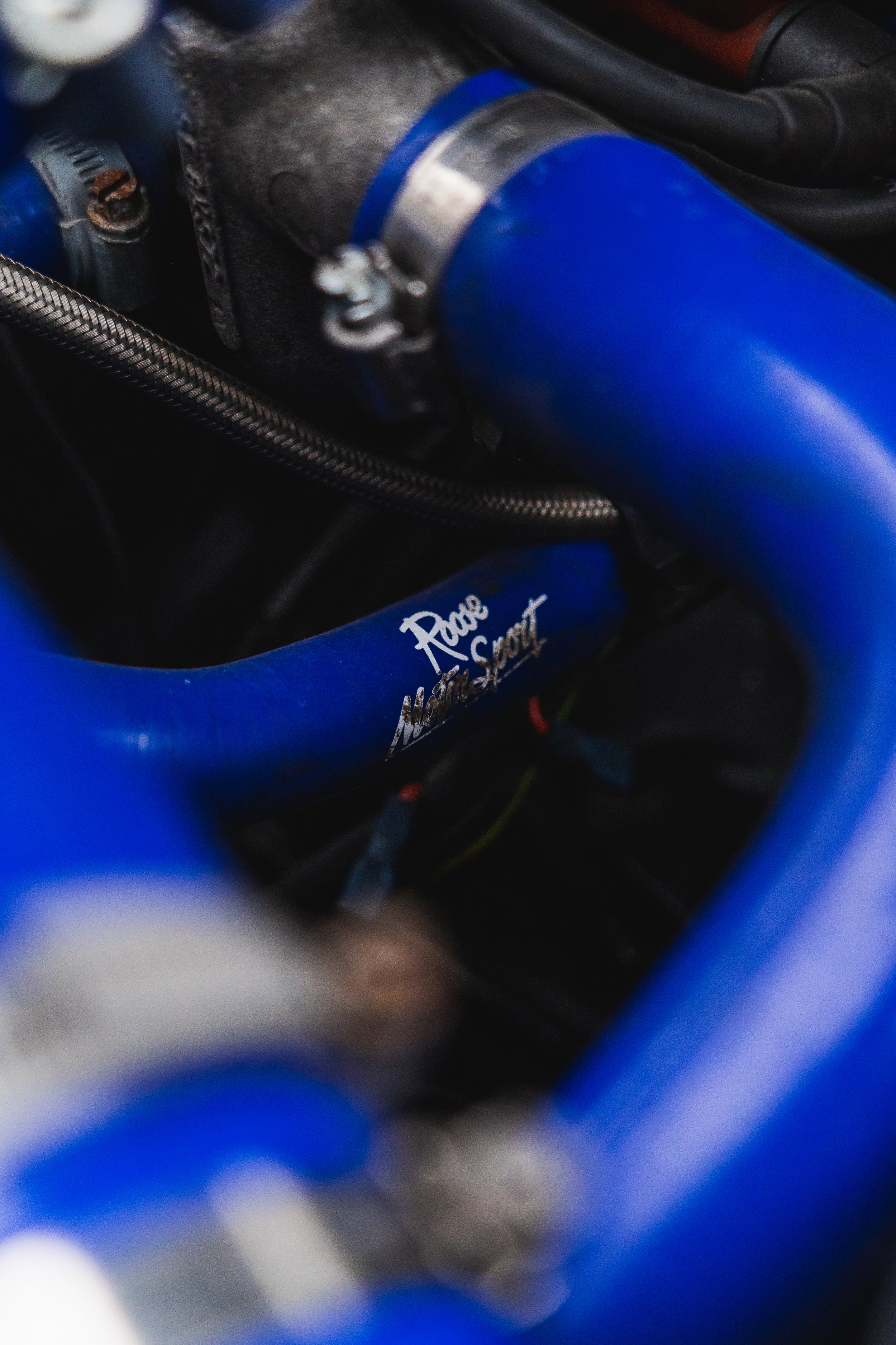 Close-up of a blue metal car part with the words "Race Nation Sport" written on it, surrounded by other metallic components and wires.