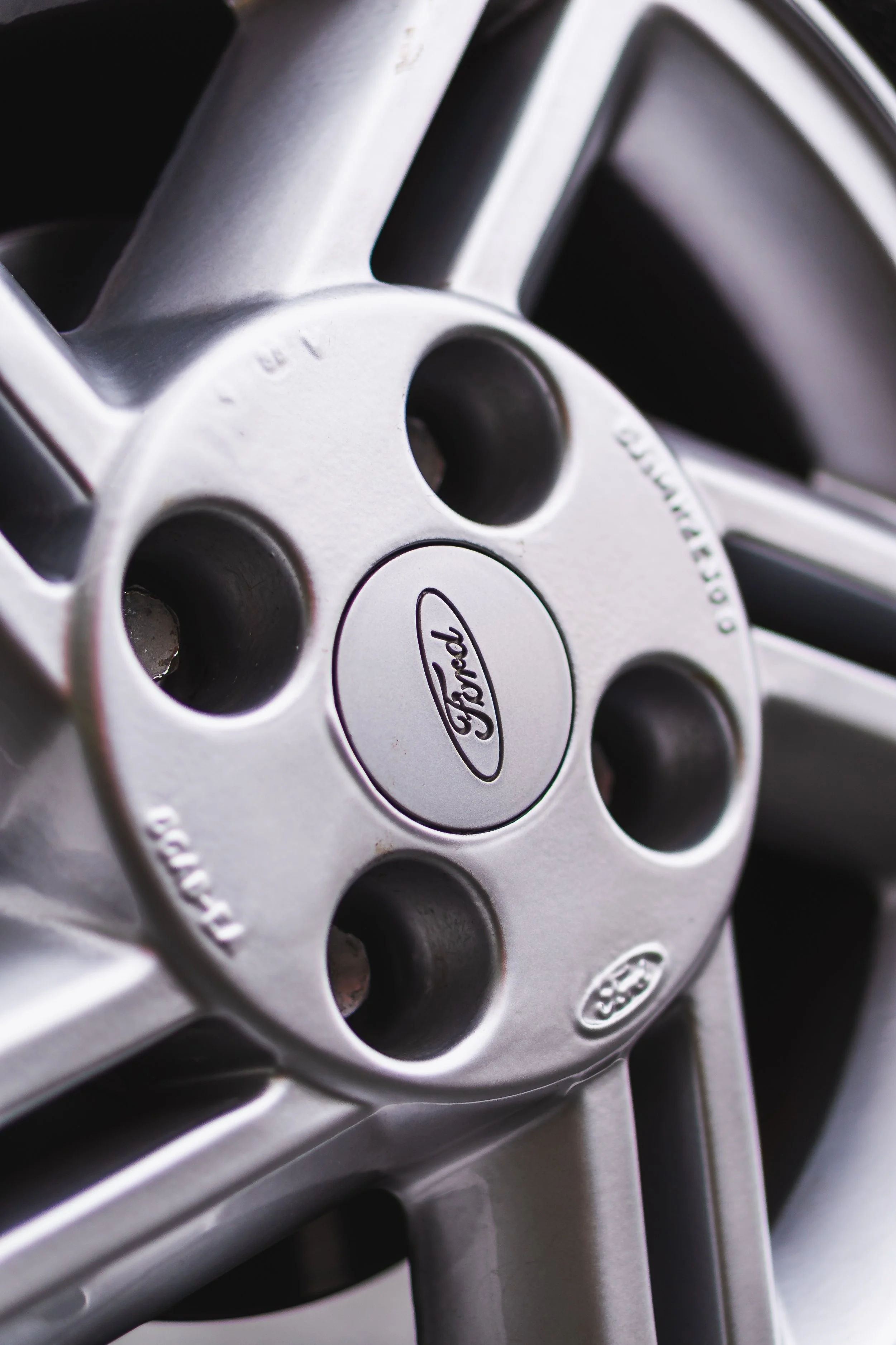 Close-up of a silver Ford car wheel rim with the Ford logo in the center