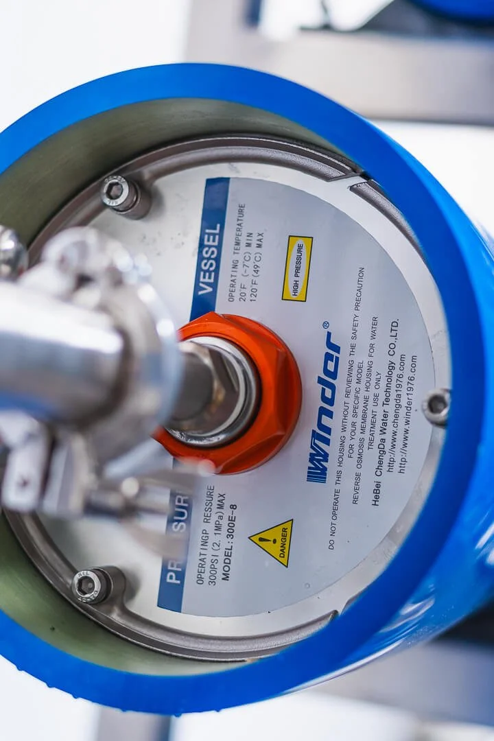 Close-up of a high-pressure vessel with a blue rim and a white label displaying operating temperature and pressure limits.