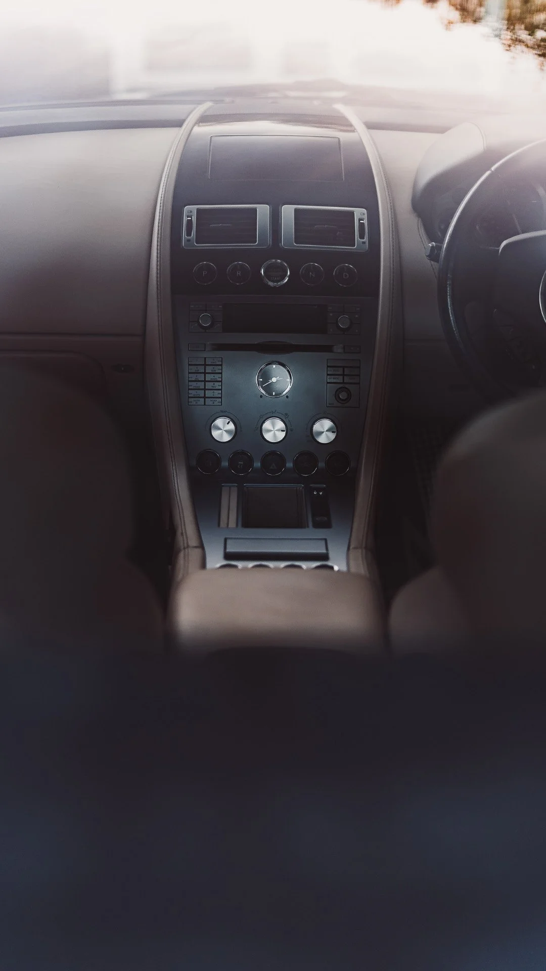 Interior of a luxury car's dashboard showing control panels, a speedometer, and a steering wheel.