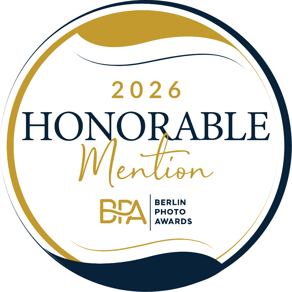 Award badge for the 2026 Berlin Photo Awards Honorable Mention, featuring a black, white, and gold circular design.